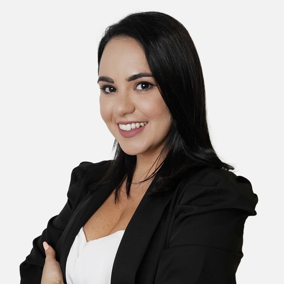 Donna sorridente con capelli scuri e giacca nera.
