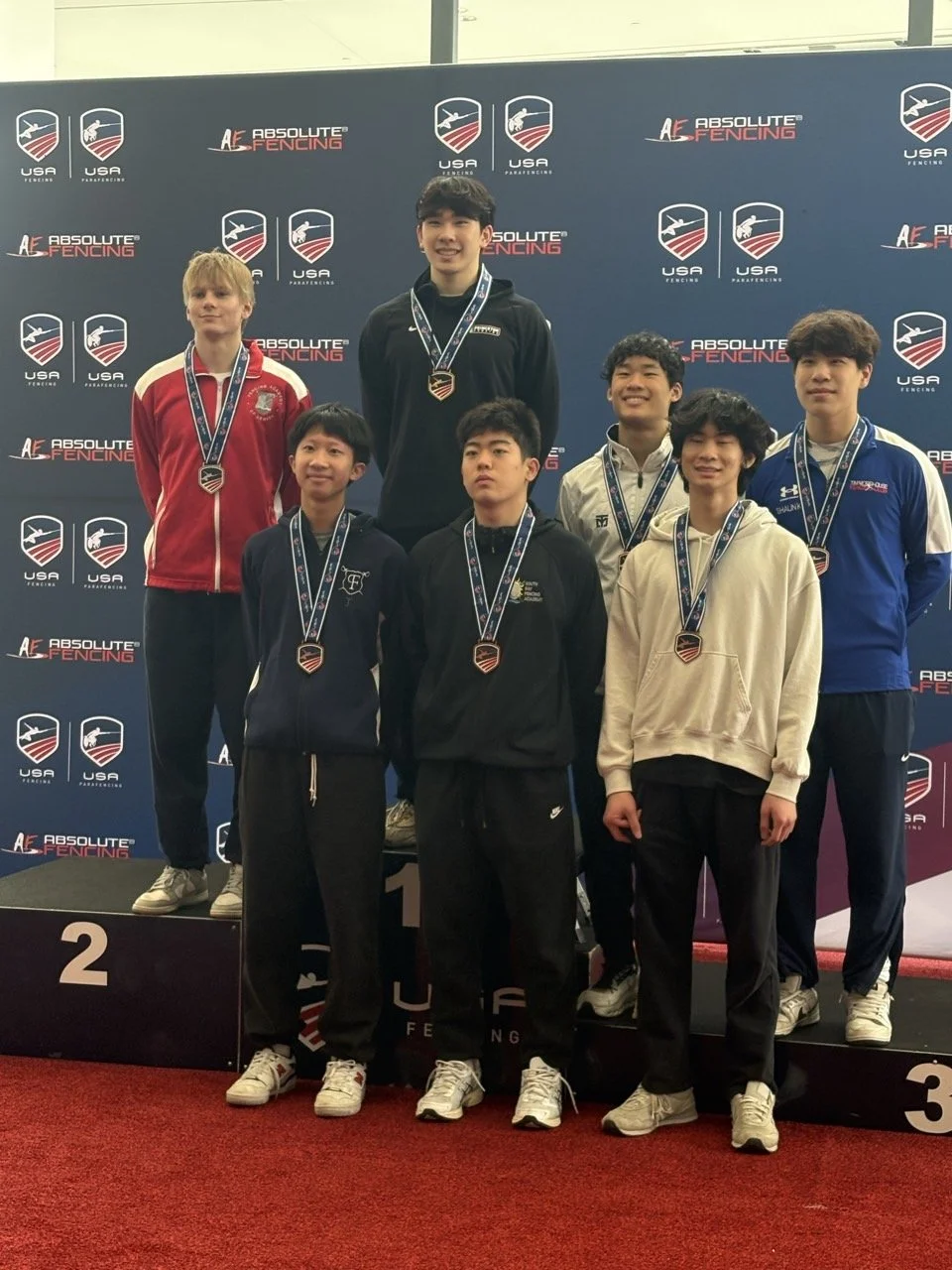 Group of male fencing athletes on the podium holding medals and certificates at the 2025 Summer Nationals in Milwaukee, Wisconsin.