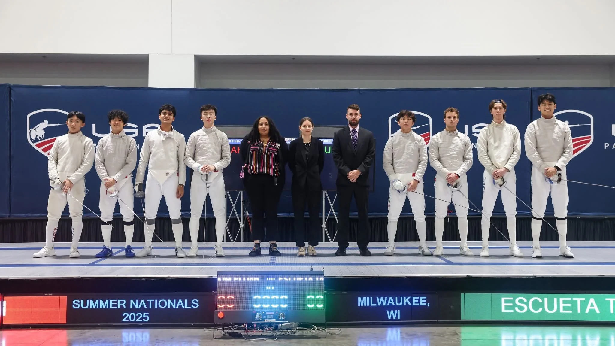 Fencing team standing on a competition platform during the 2025 Summer Nationals in Milwaukee, WI.