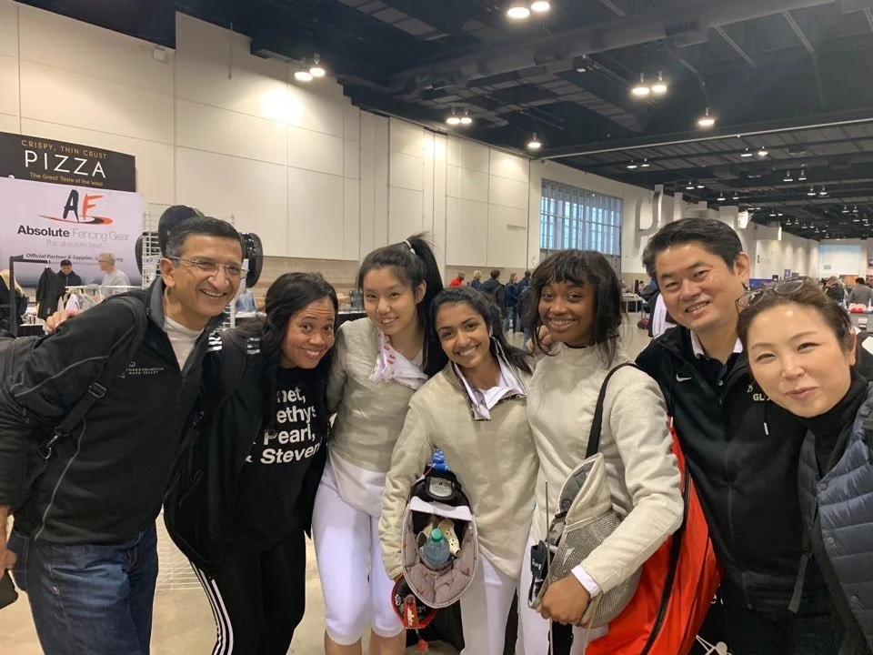 Group of seven people smiling and posing together in a large indoor space, possibly at an event or convention.