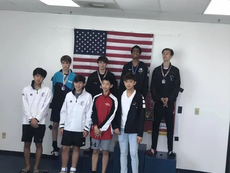 Group of young athletes on a podium with medals, standing in front of an American flag