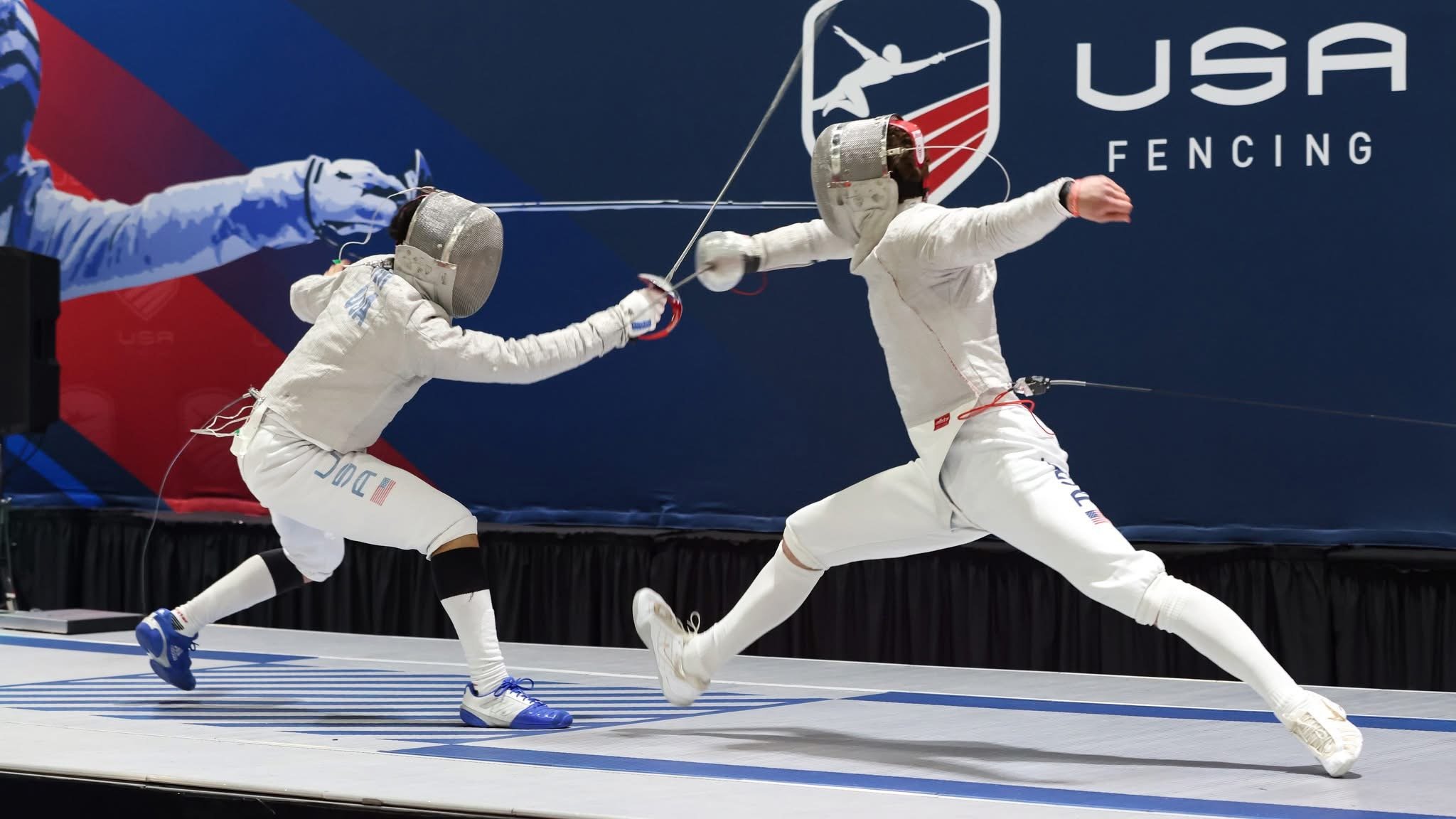 Two fencers in white gear engaging in a fencing match, with a large banner showing USA fencing symbol in the background.
