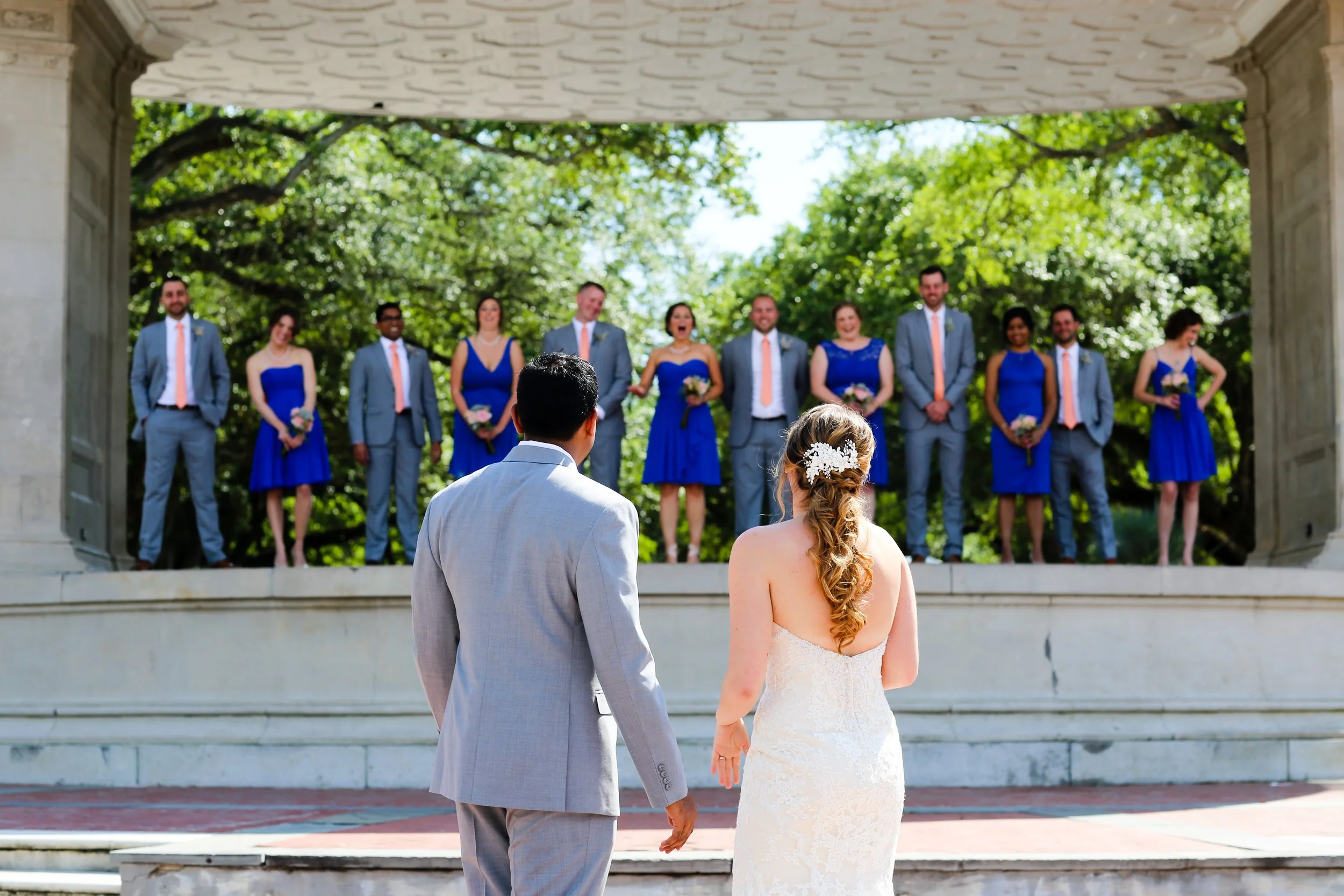 Bride and groom look back at their wedding party in outdoor venue