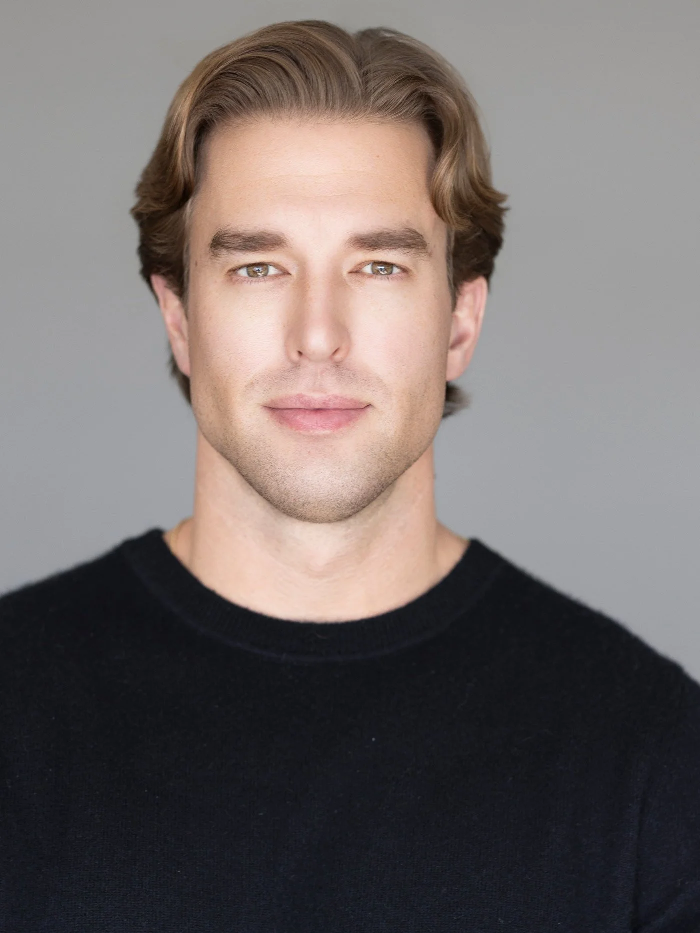 Male actor headshot wearing a black shirt against a gray background