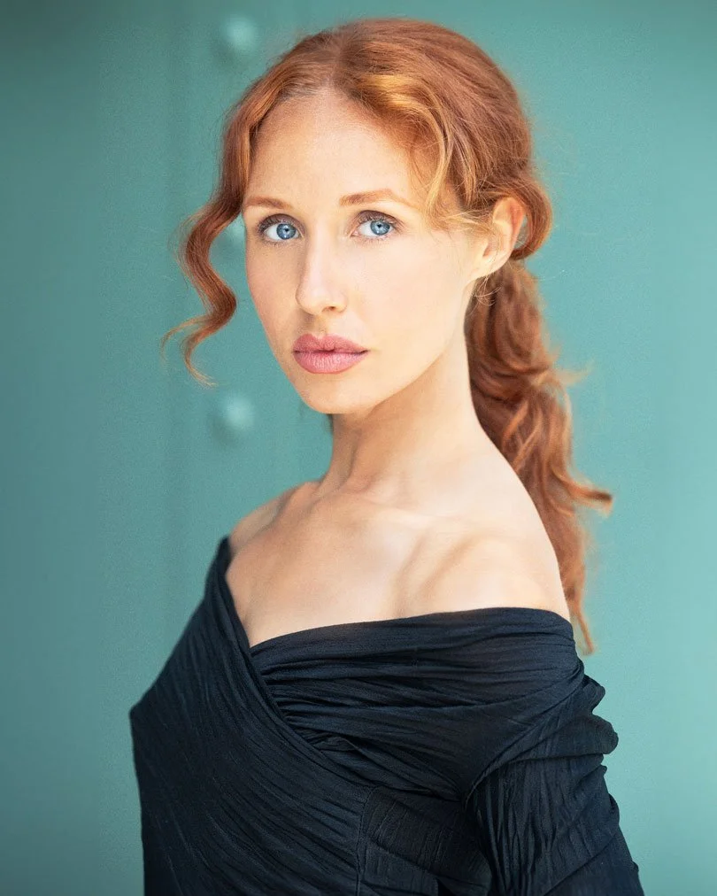 Red-haired performer portrait against a teal background