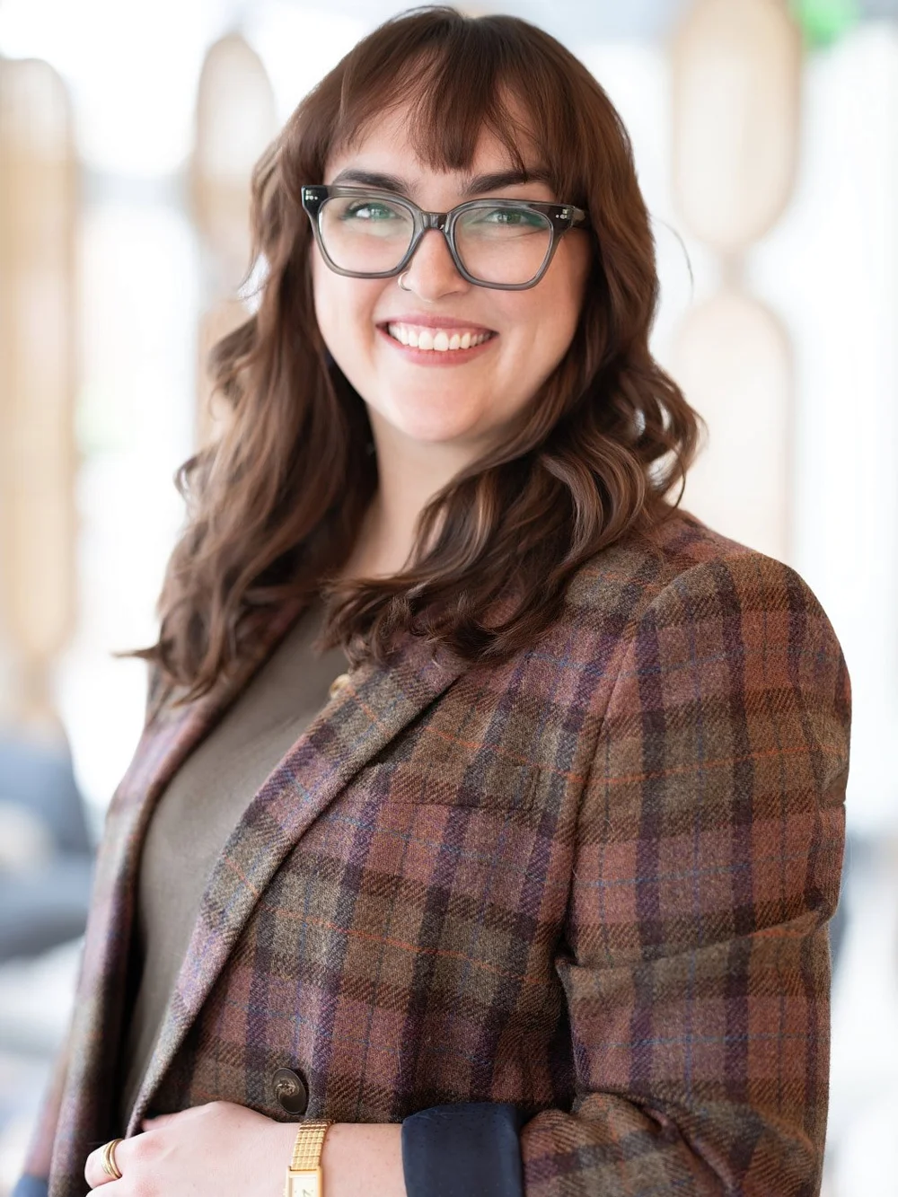 Kait standing in a plaid blazer in a bright professional setting