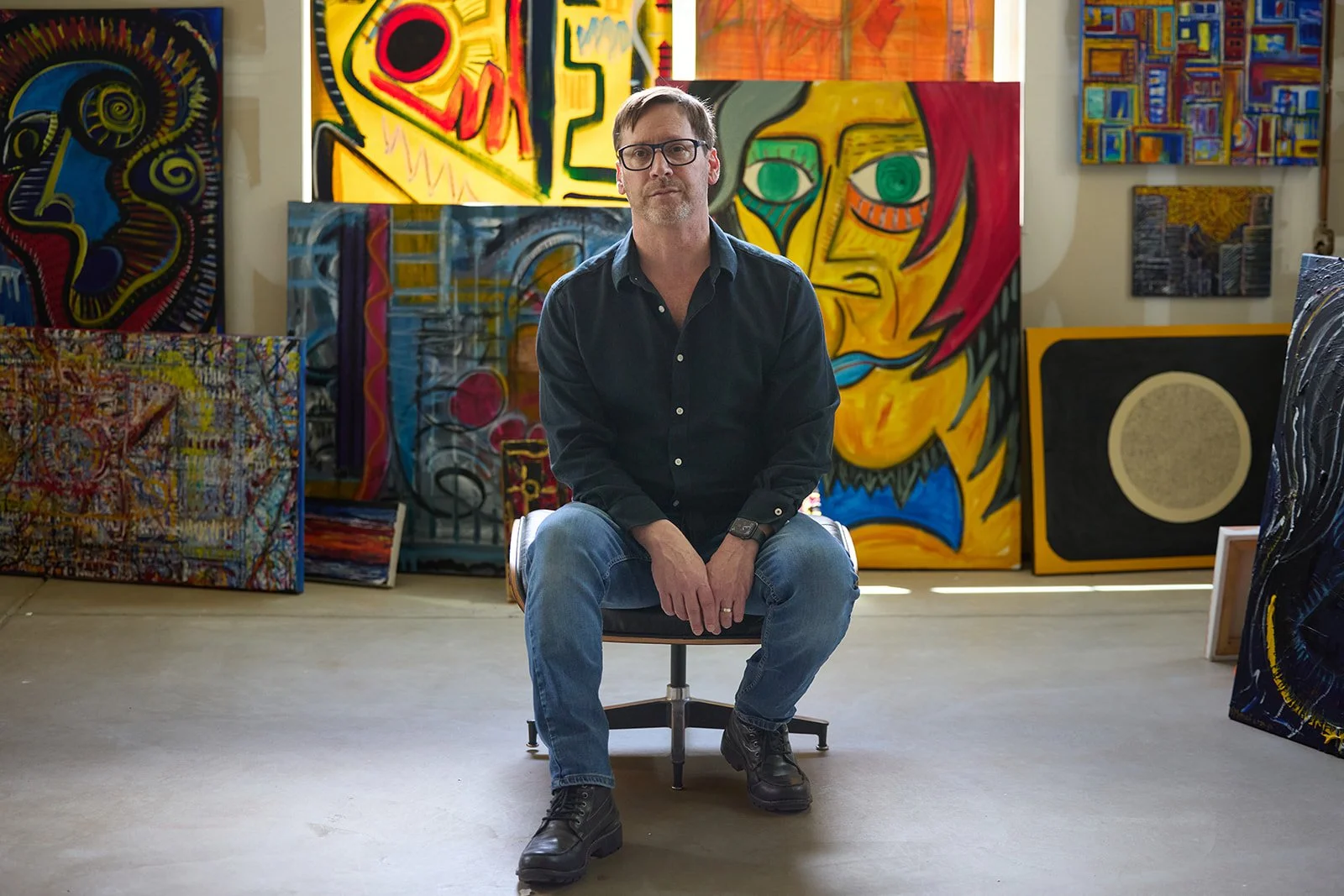 Artist photographed in his Denver studio surrounded by his paintings &mdash; personal branding photography by Draper Studios