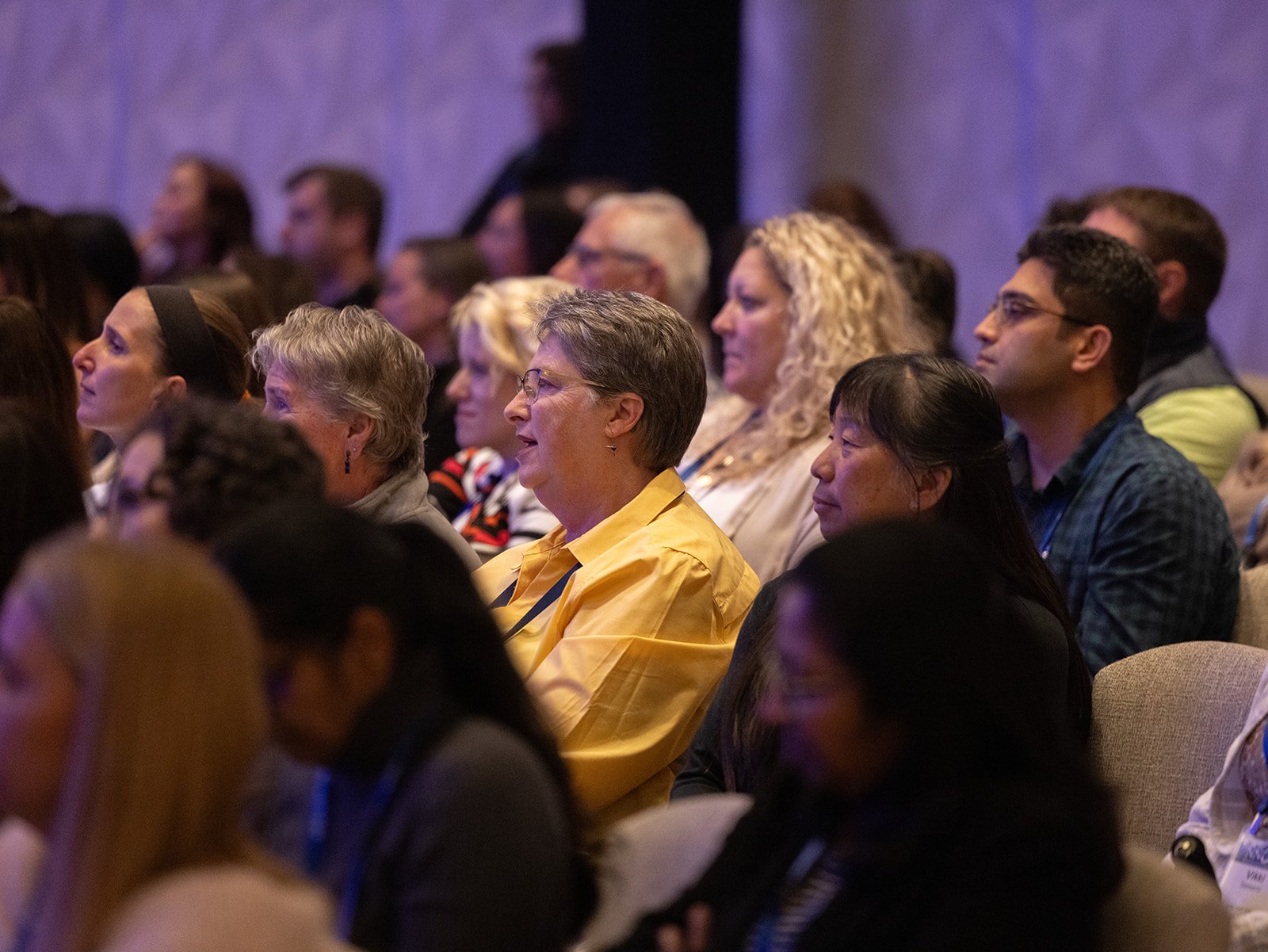 Audience members at a conference or seminar, seated and listening attentively.