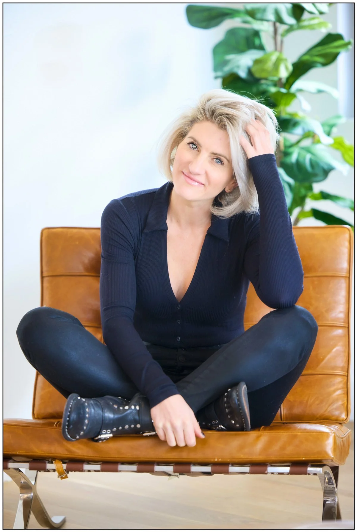 Personal branding portrait of a woman seated in a leather chair photographed by Draper Studios