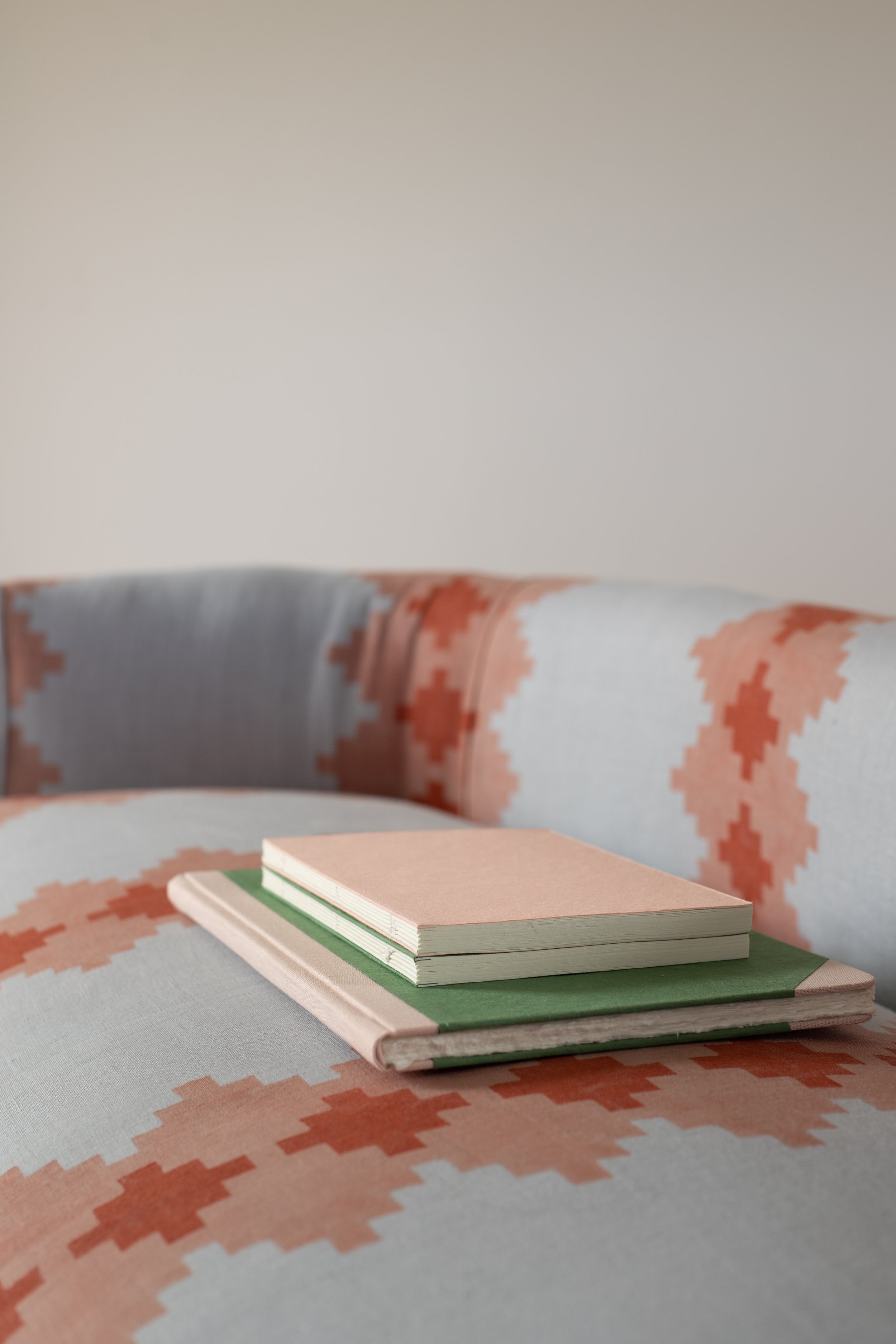 Recycled cotton notebooks laying on our upholstered sofa.