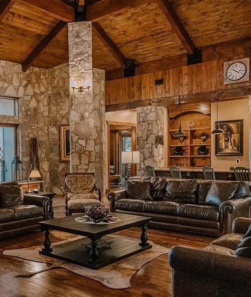 Spacious luxury living room interior at Asante lodging in Dripping Springs Texas with stone fireplace and seating
