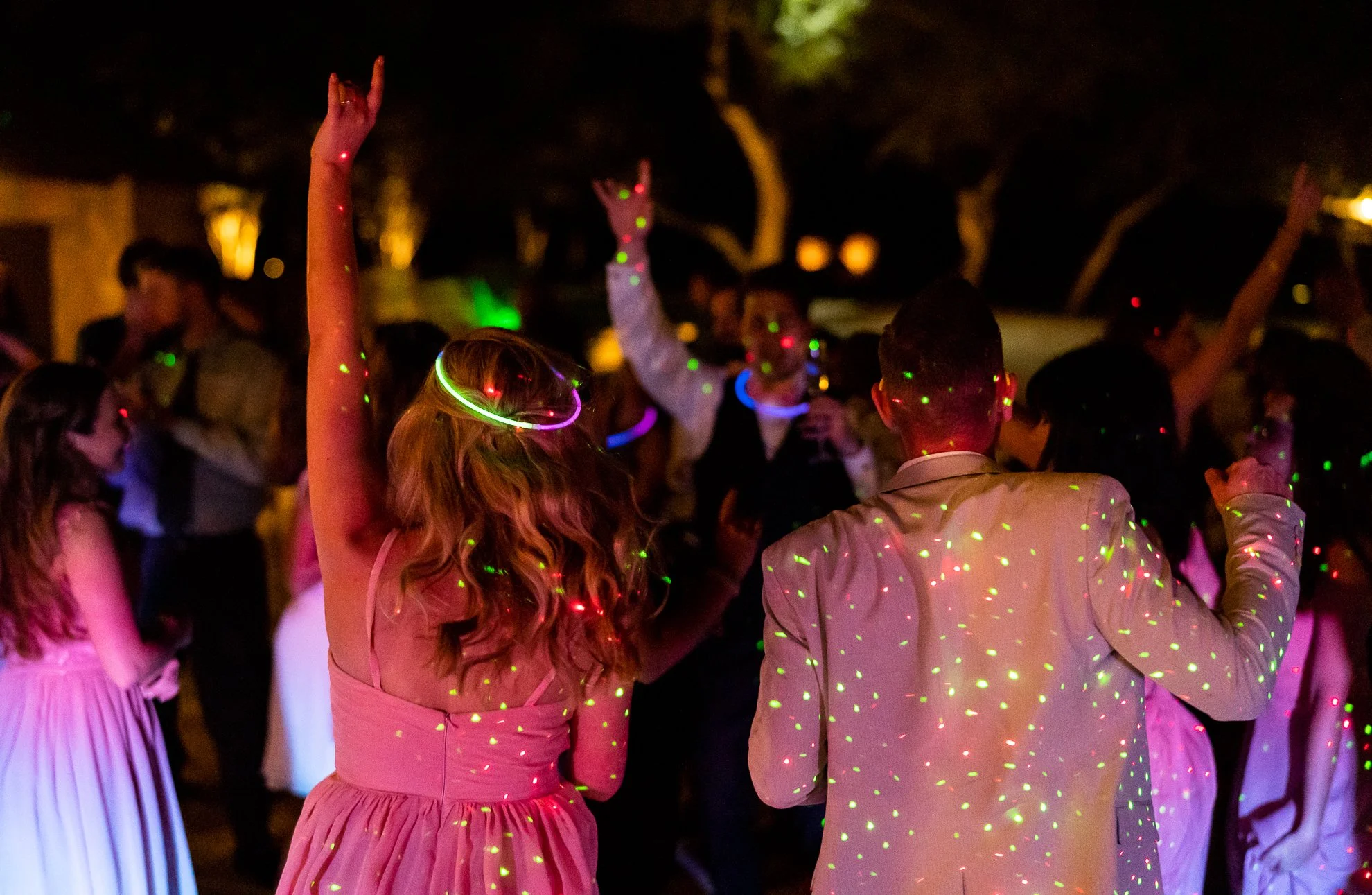 People dancing at a party with colorful laser lights at night.