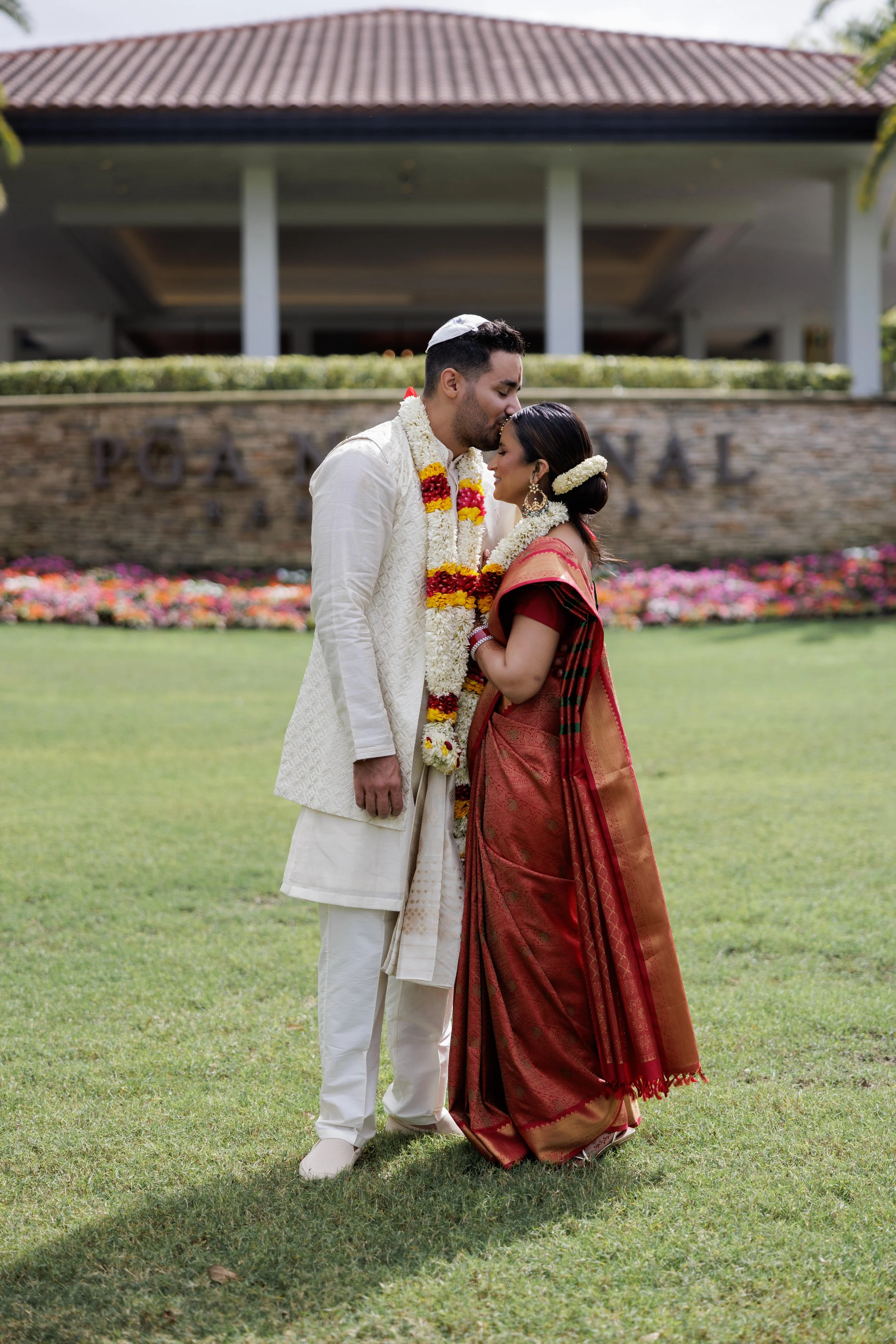 Groom kisses his bride during their multicultural wedding at PGA National Resort in Palm Beach Gardens, captured by South Florida wedding photographer Alekandra London of Nine One Four & Co.