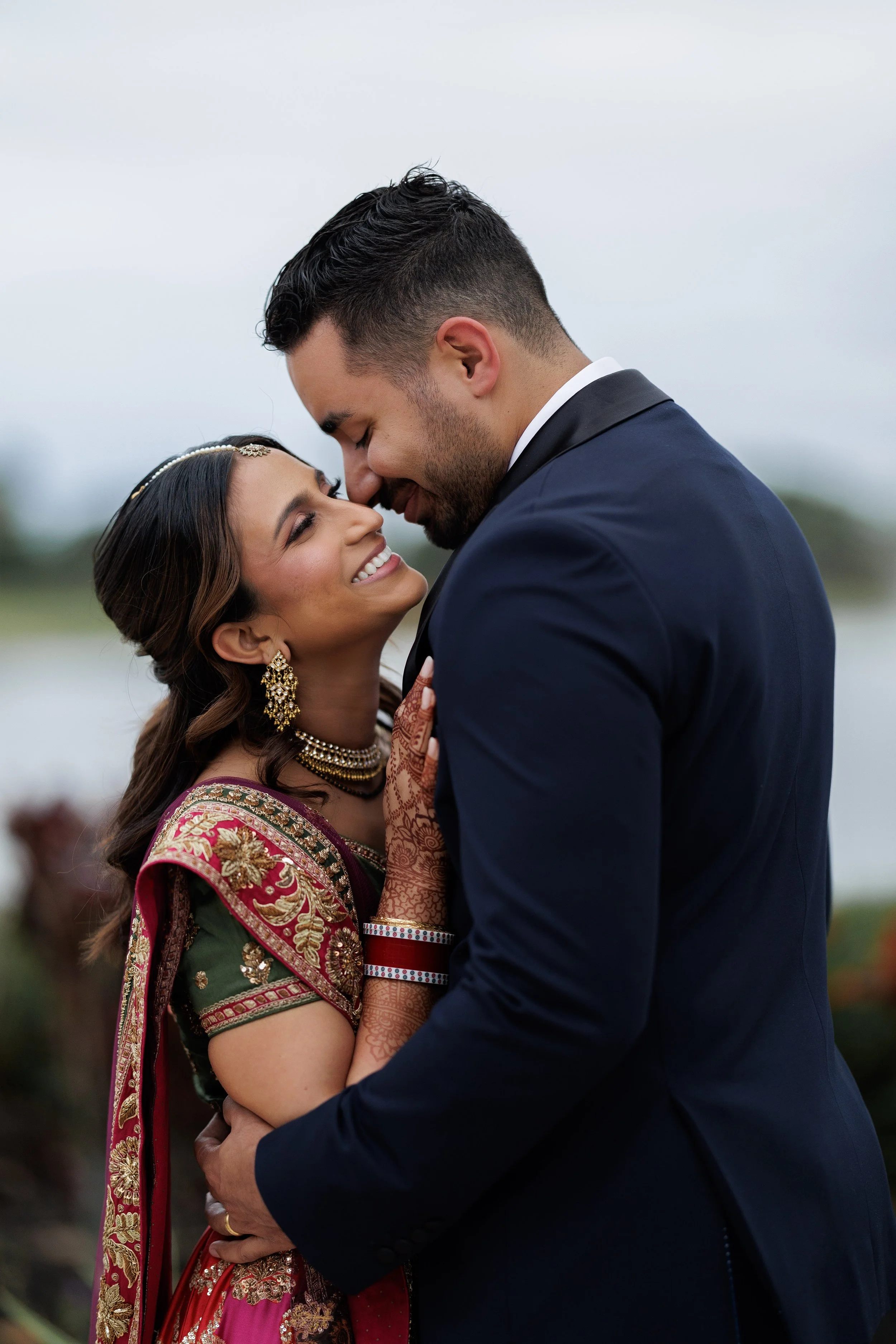 A couple in traditional Indian attire sharing an intimate moment outdoors.