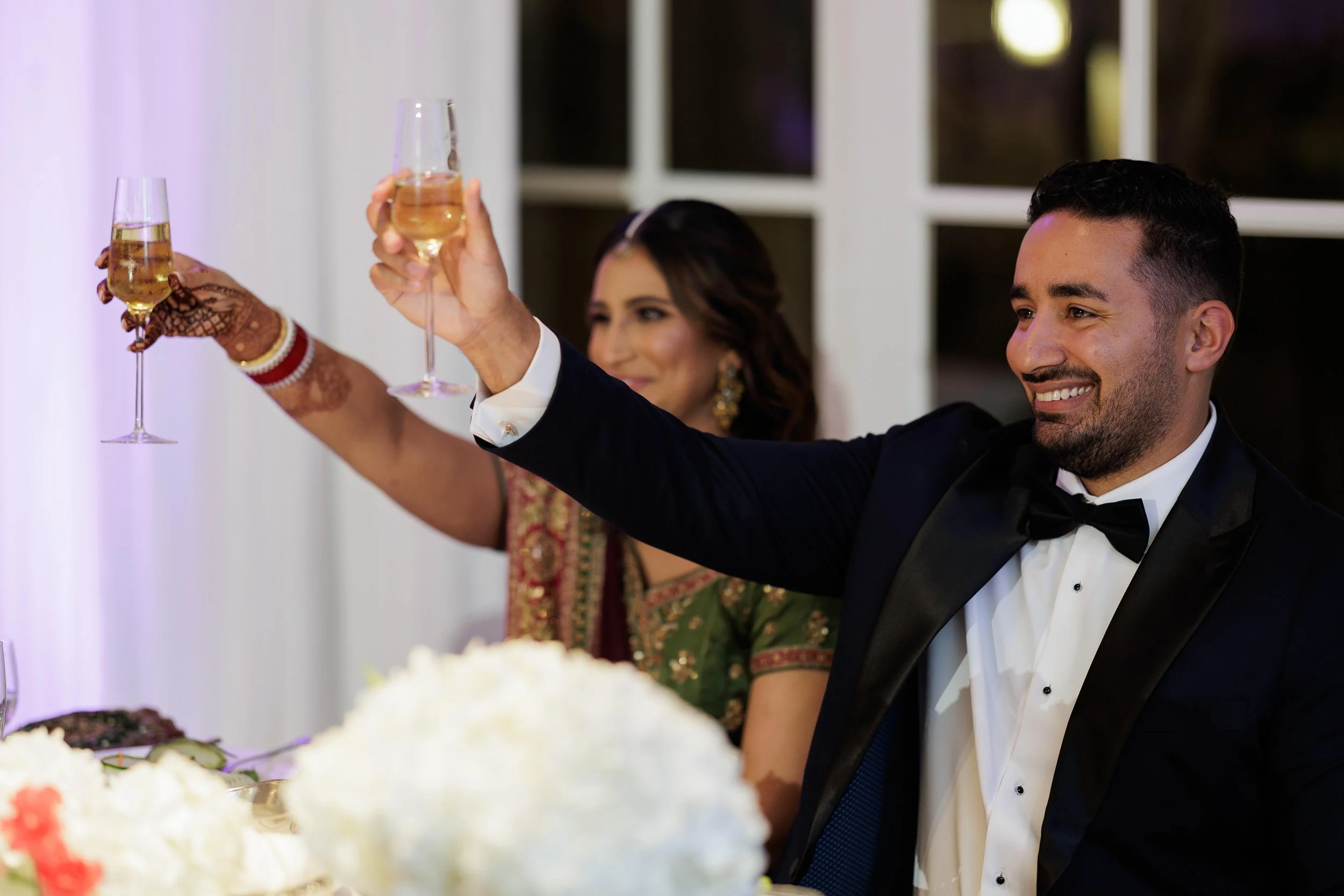 A man and a woman in formal attire raising champagne glasses in a toast at a celebration event.