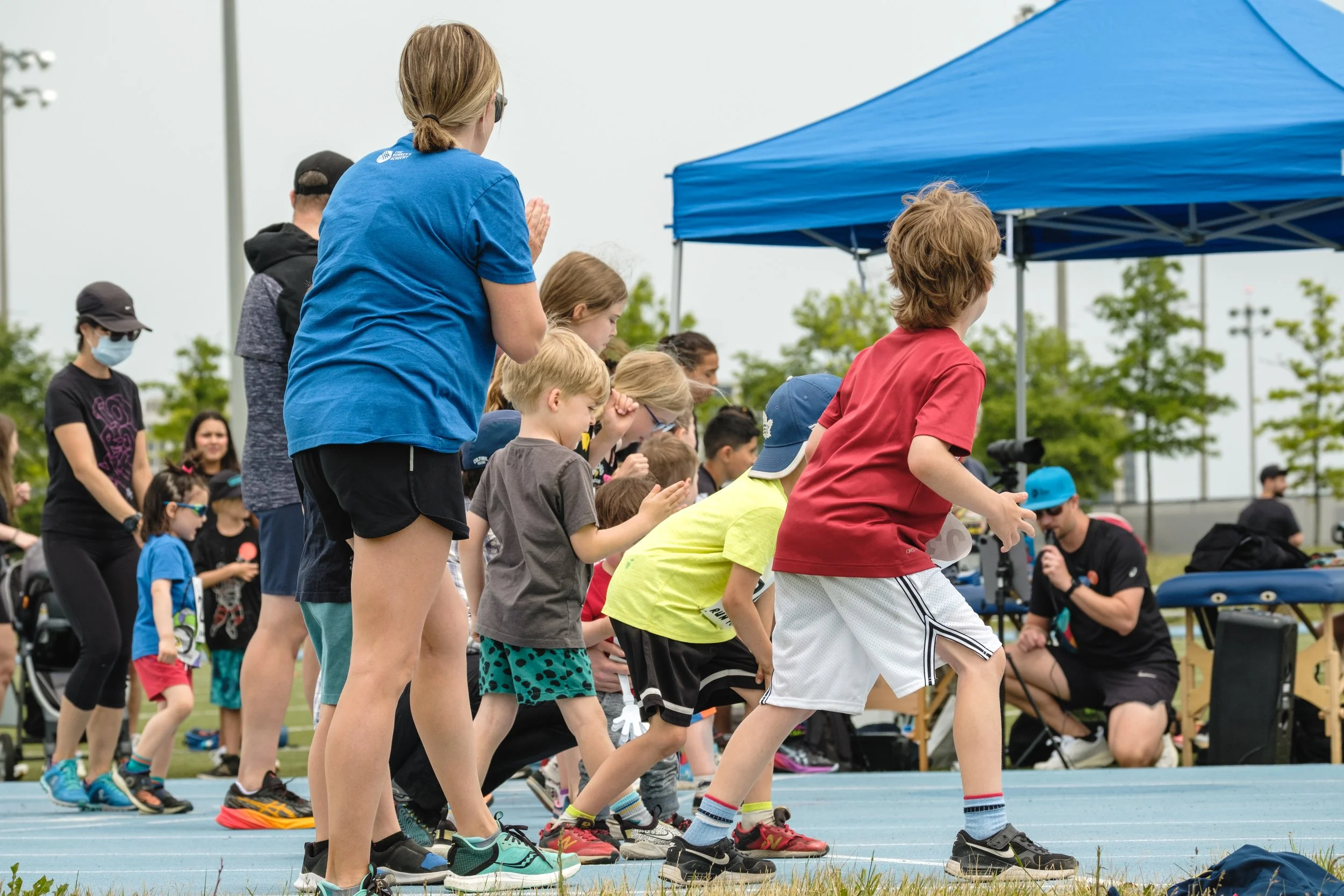A group of children on a track at a start line, waiting to race