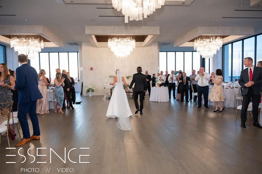 Bride and groom walk to their table during their Chicagoland wedding reception with lime washed walls and chandeliers.