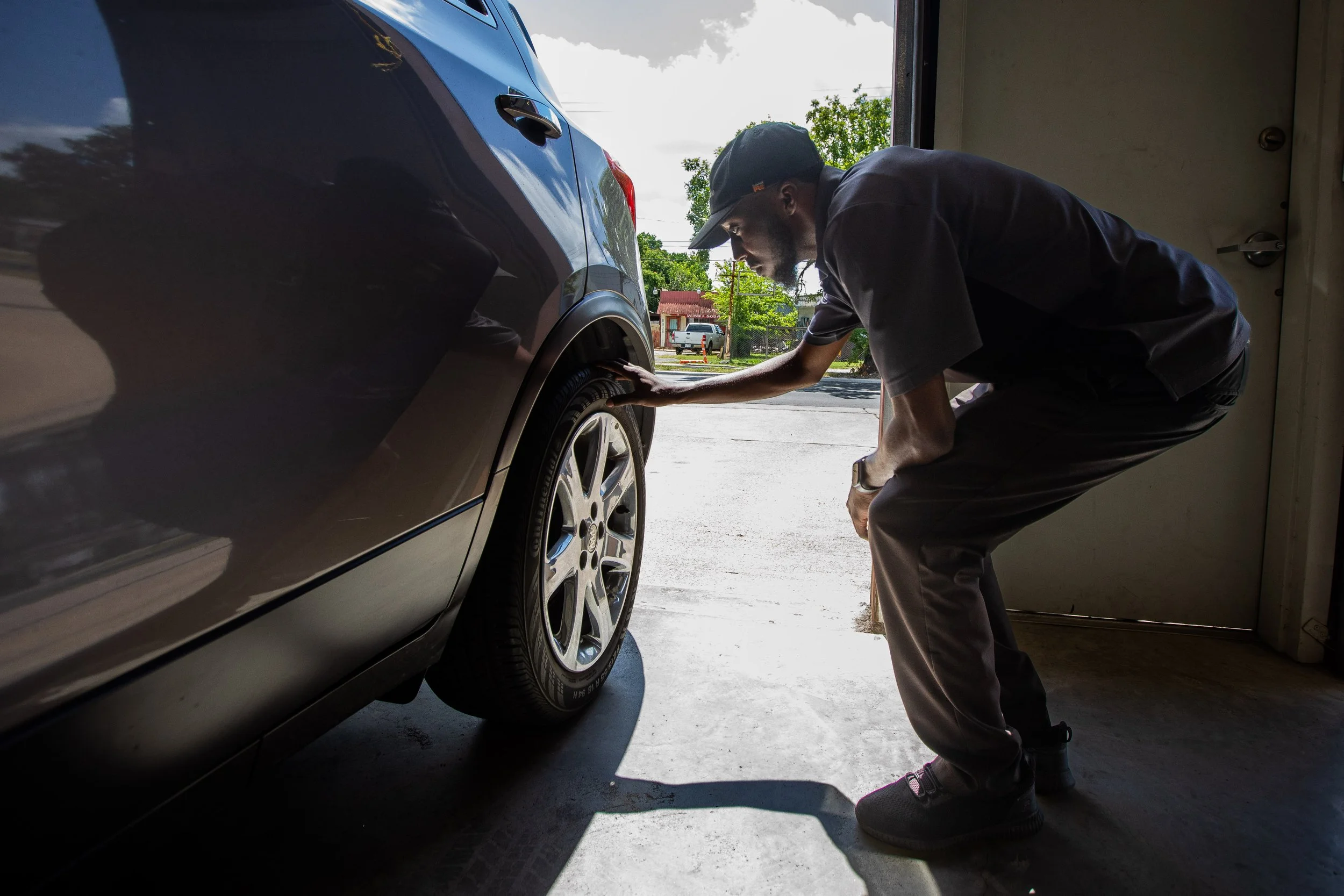 Cory Davis inspects a car as customers wait outside at Larry’s Auto Inspection on Tuesday, June 13, 2023 in Houston.