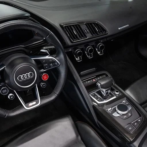 Close-up of the interior dashboard of an Audi car, showing the steering wheel, infotainment controls, and gear shifter.