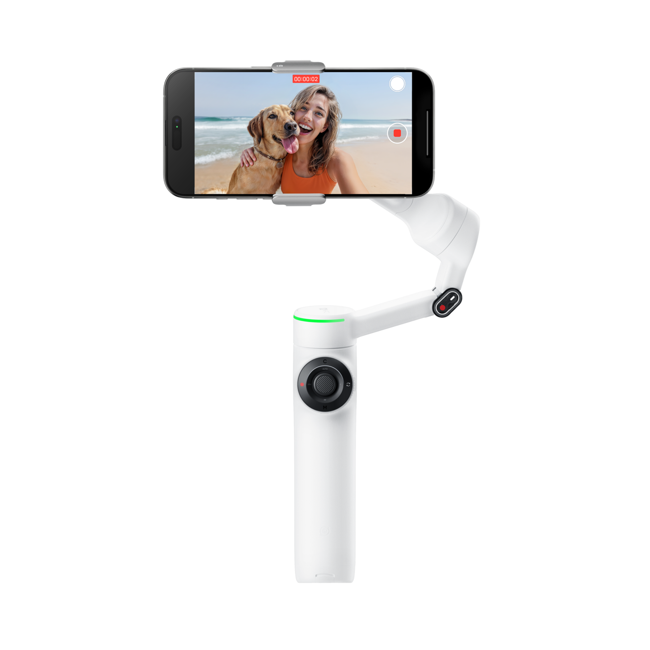 A white handheld gimbal stabilizer with a mounted smartphone recording a selfie of a woman and a dog on a beach.