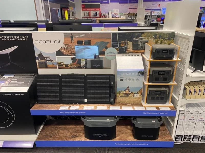 Display of portable solar power systems and accessories at an electronics store, featuring solar panels, chargers, and associated equipment.