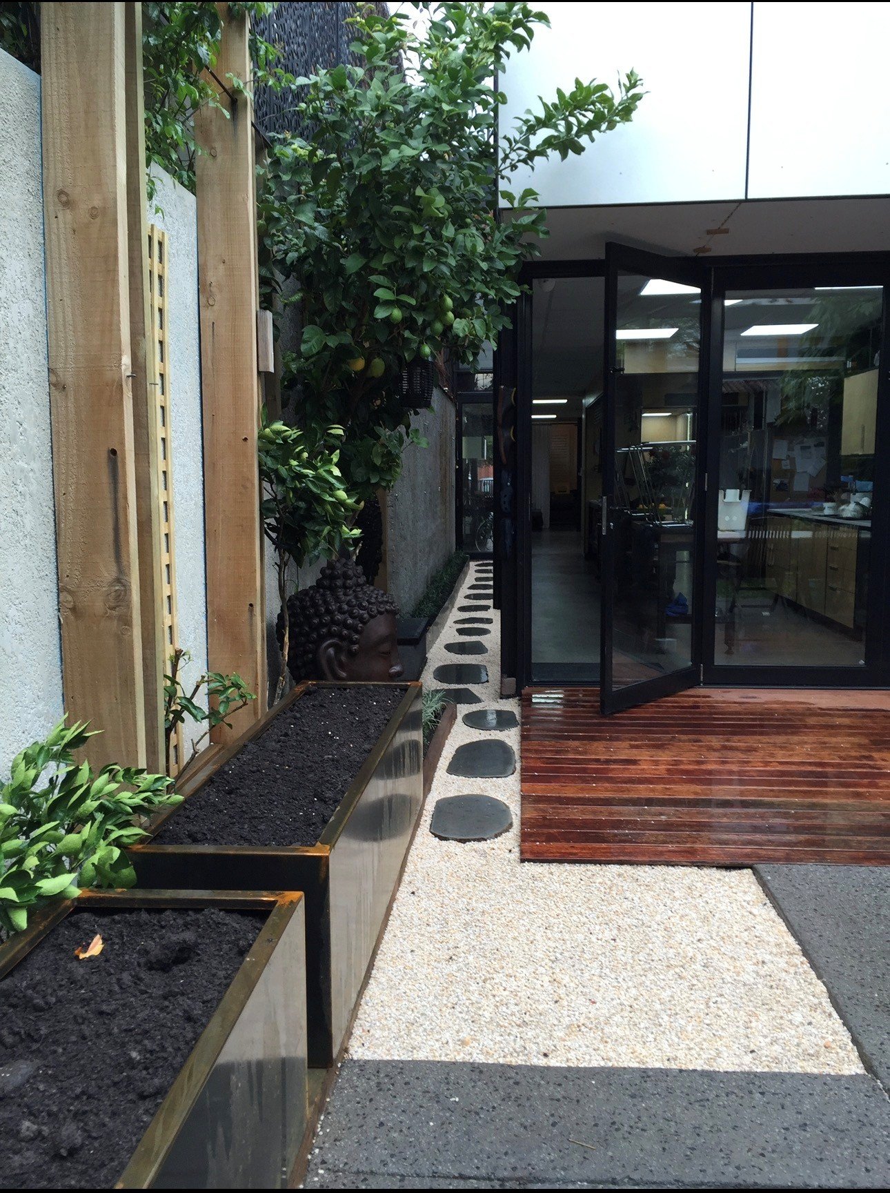 odern outdoor courtyard design featuring vertical timber cladding, rusted corten steel planters, and architectural concrete steps in a Fitzroy North residential project.