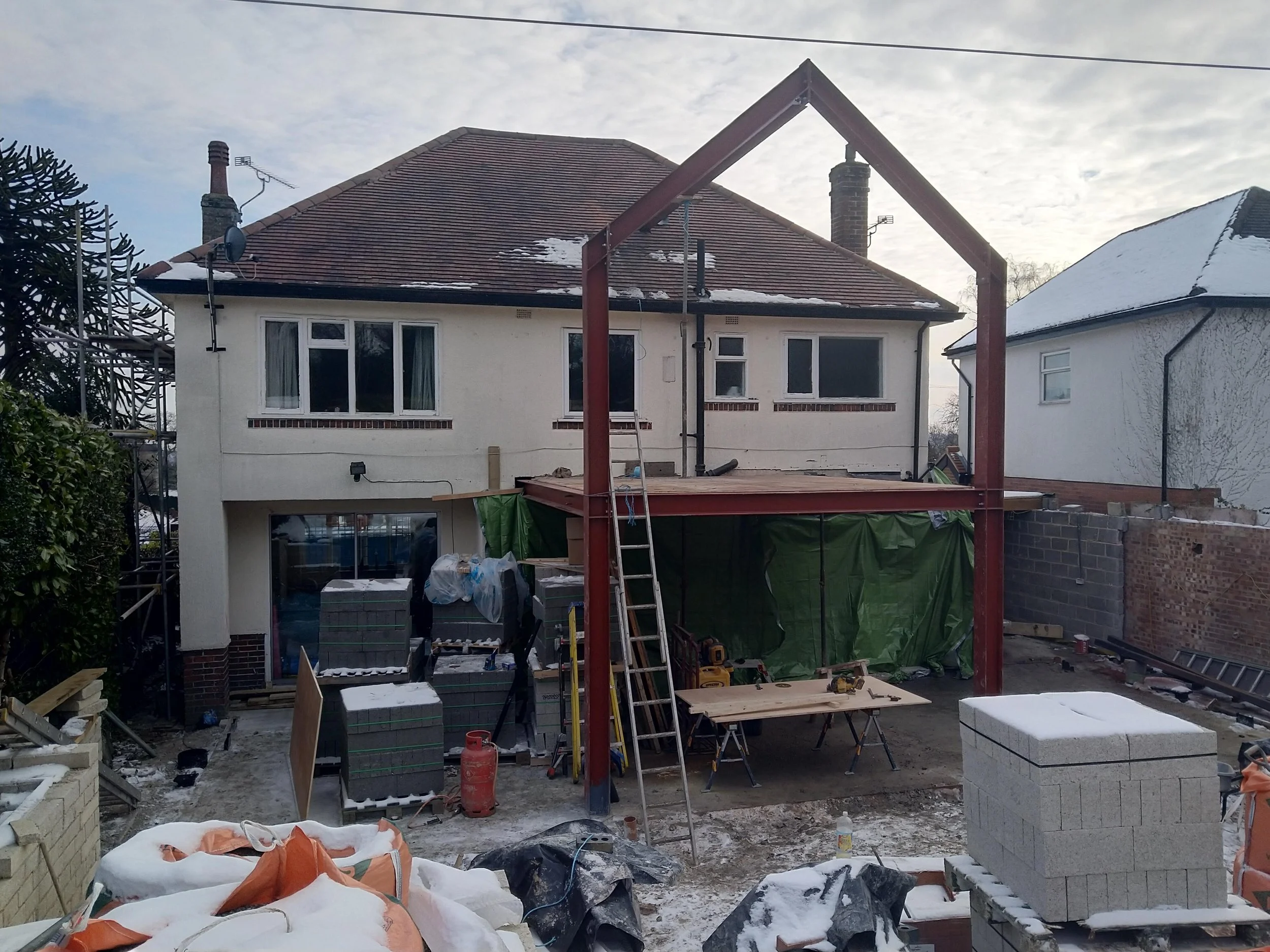 Rear view of the active residential construction site in Millhouses showing two-storey structural steelwork and masonry installation.