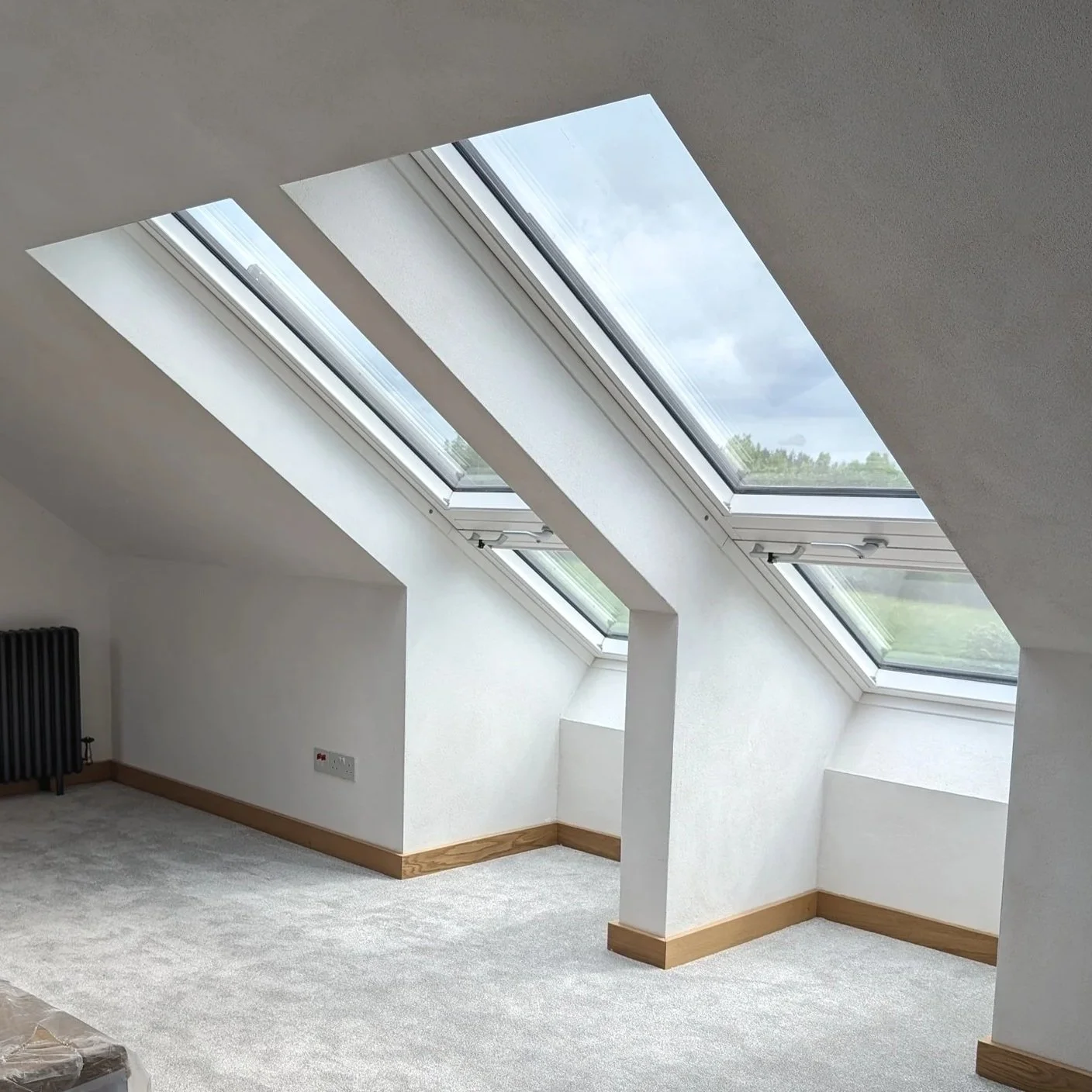 Conversion loft bedroom showing open Velux Cabrio roof windows, transformed into an integrated balcony system framing the Peak District National Park landscape at Owlet House.