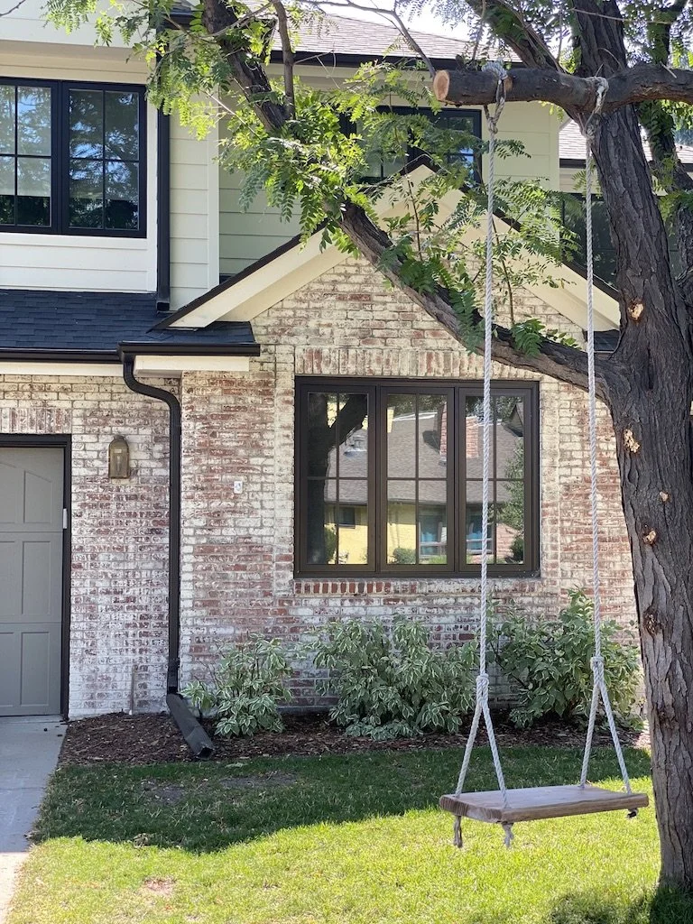 House exterior with brick wall and a tree swing in front yard.