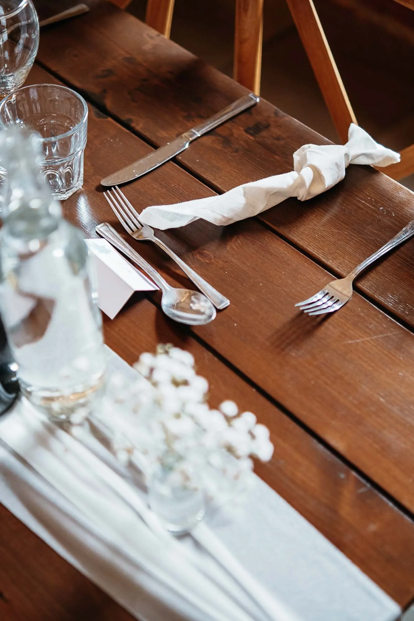 A table set with white napkins tied in knots, ready for guests to swing at the couple's entrance