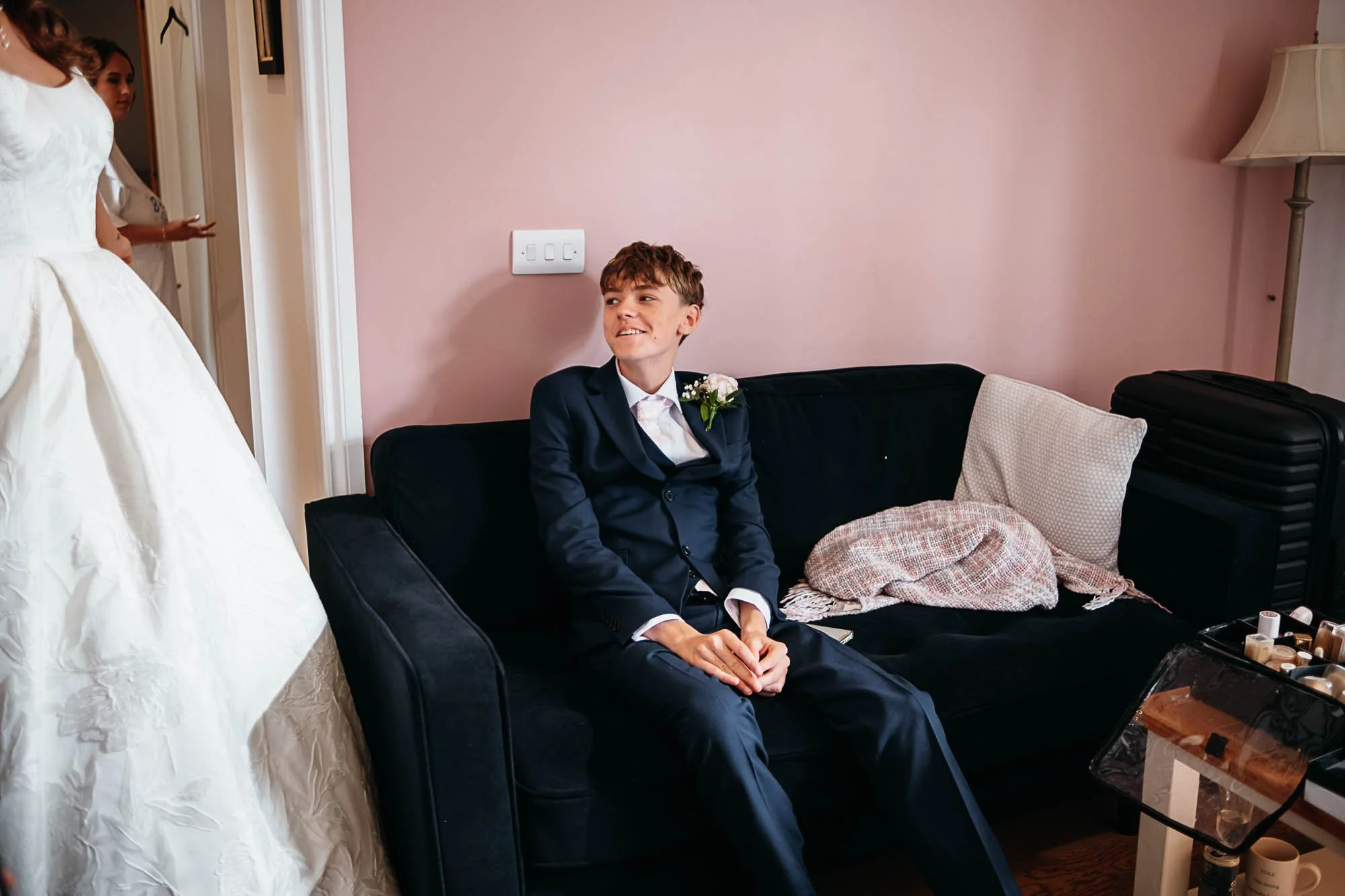 Dan sitting on a dark sofa in his suit, waiting before the ceremony