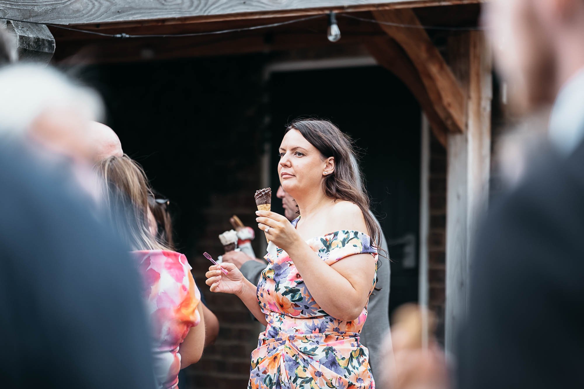 A guest in a floral dress laughing with a drink in her hand