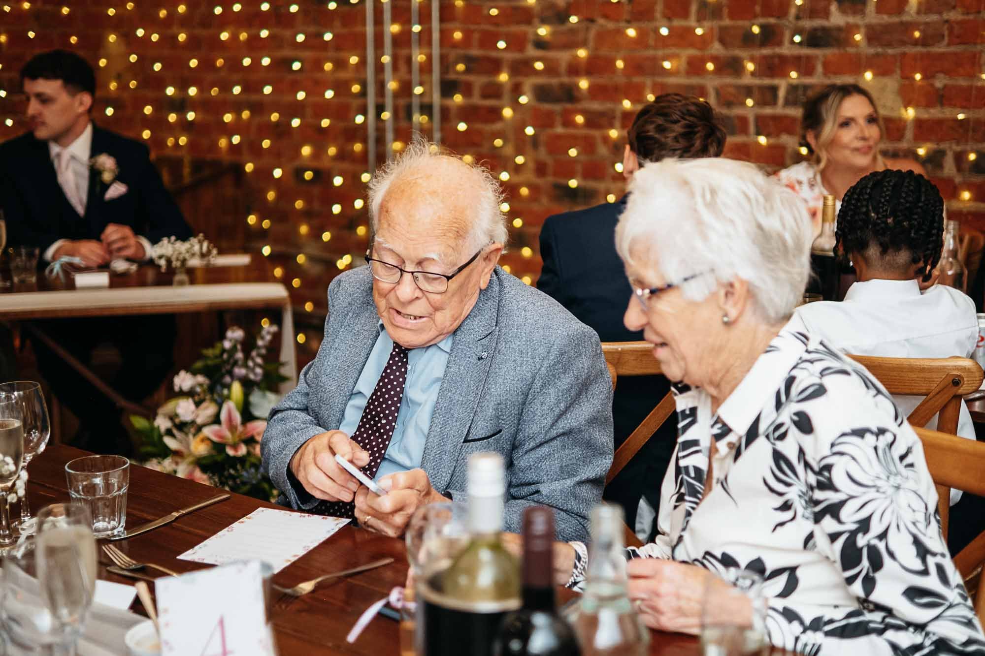 Two older guests smiling at the table under fairy lights