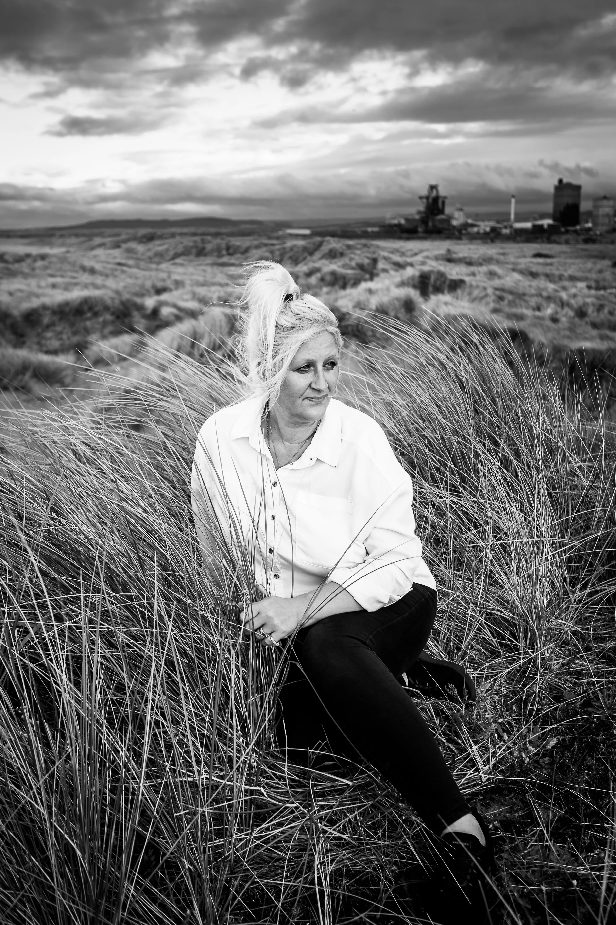 women sits in long grass on sandunes