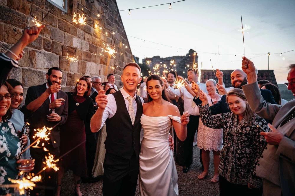 Bride and groom surrounded by sparklers during an evening wedding at Danby Castle