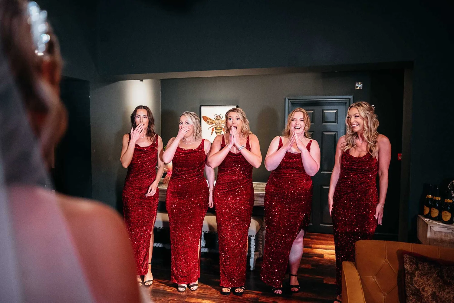 Bridesmaids in red sequinned dresses reacting as they see the bride at The Croft Hotel