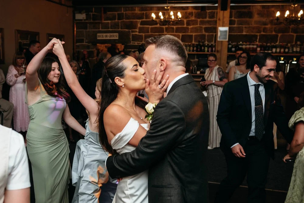 Bride and groom kissing on the dance floor during an evening wedding reception at Danby Castle