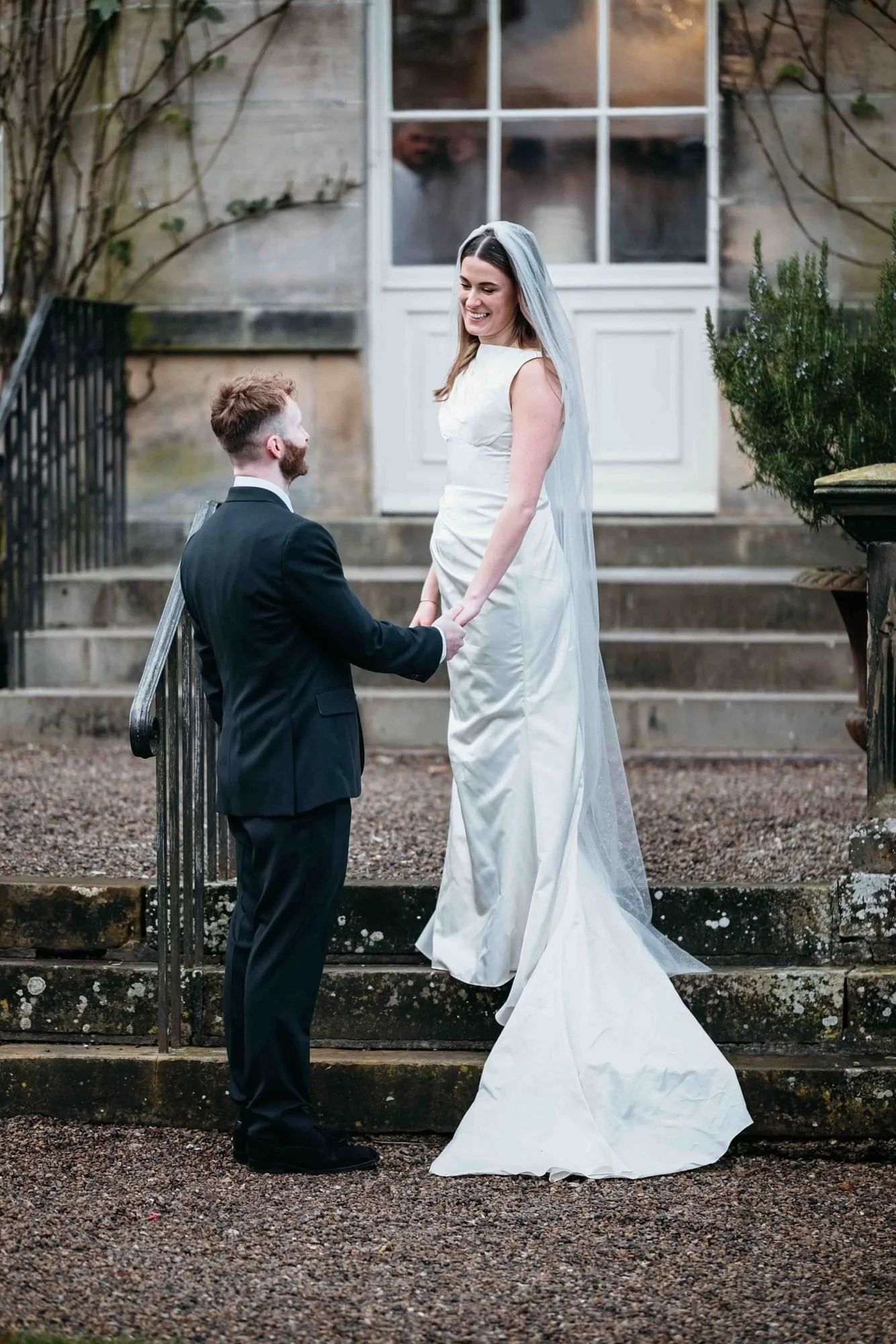 Couple holding hands on the stone steps of the Main House at Middleton Lodge