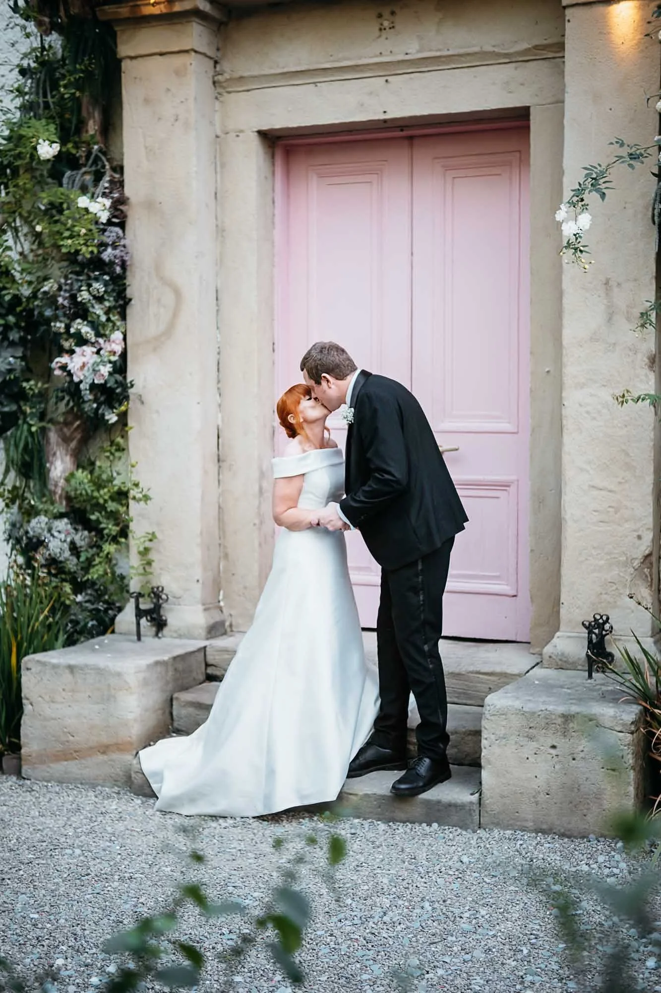 Bride and groom kissing on the steps at the pink door of The Croft Hotel, Croft-on-Tees