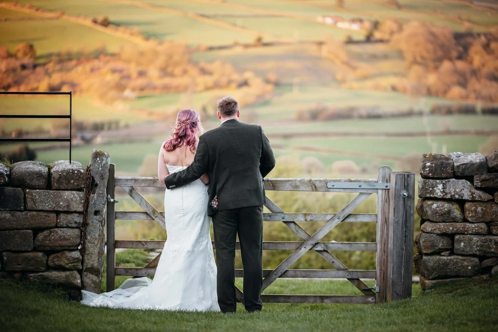 Bride and groom at the gate overlooking the Esk Valley at Danby Castle