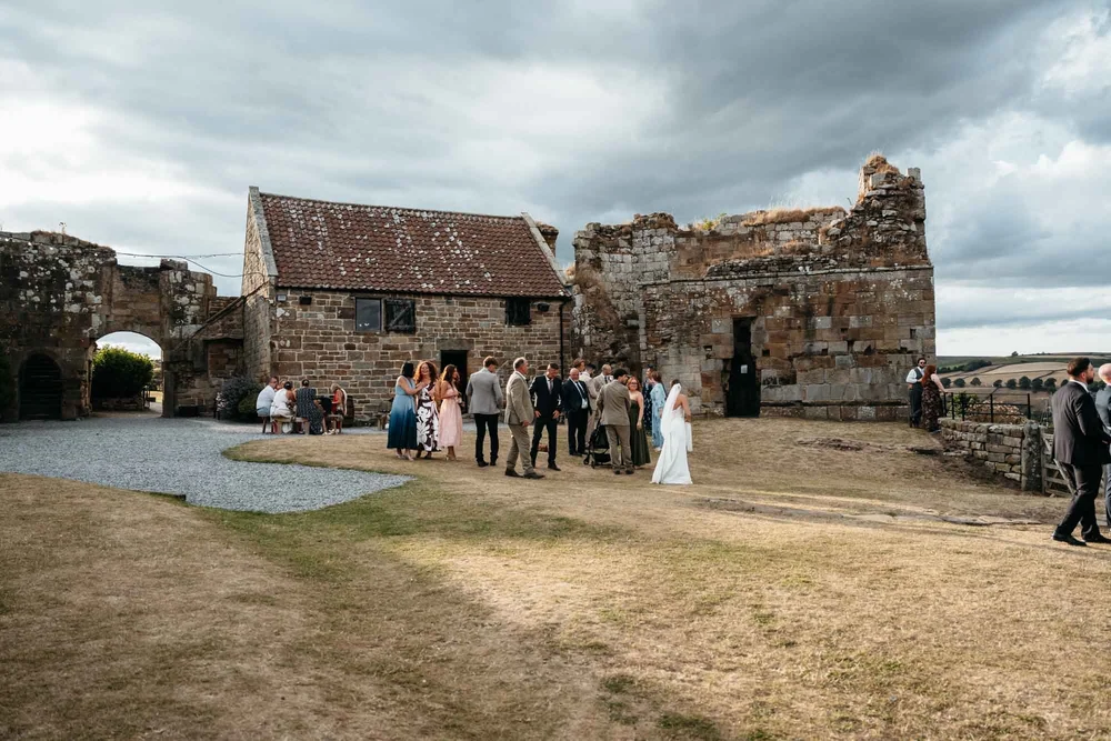 Wedding guests enjoying drinks among the castle ruins at Danby Castle