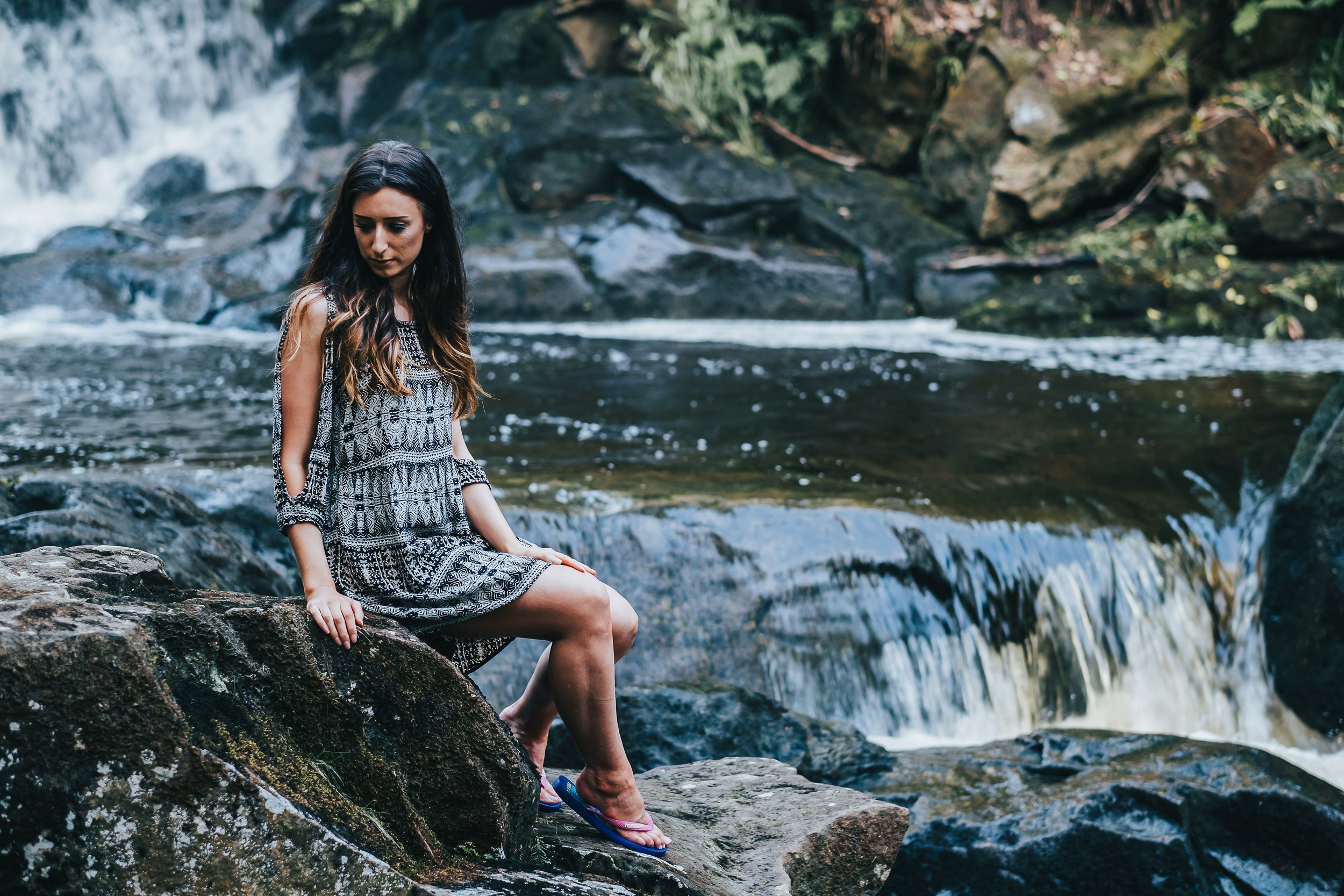 Women sits on rocks next to river