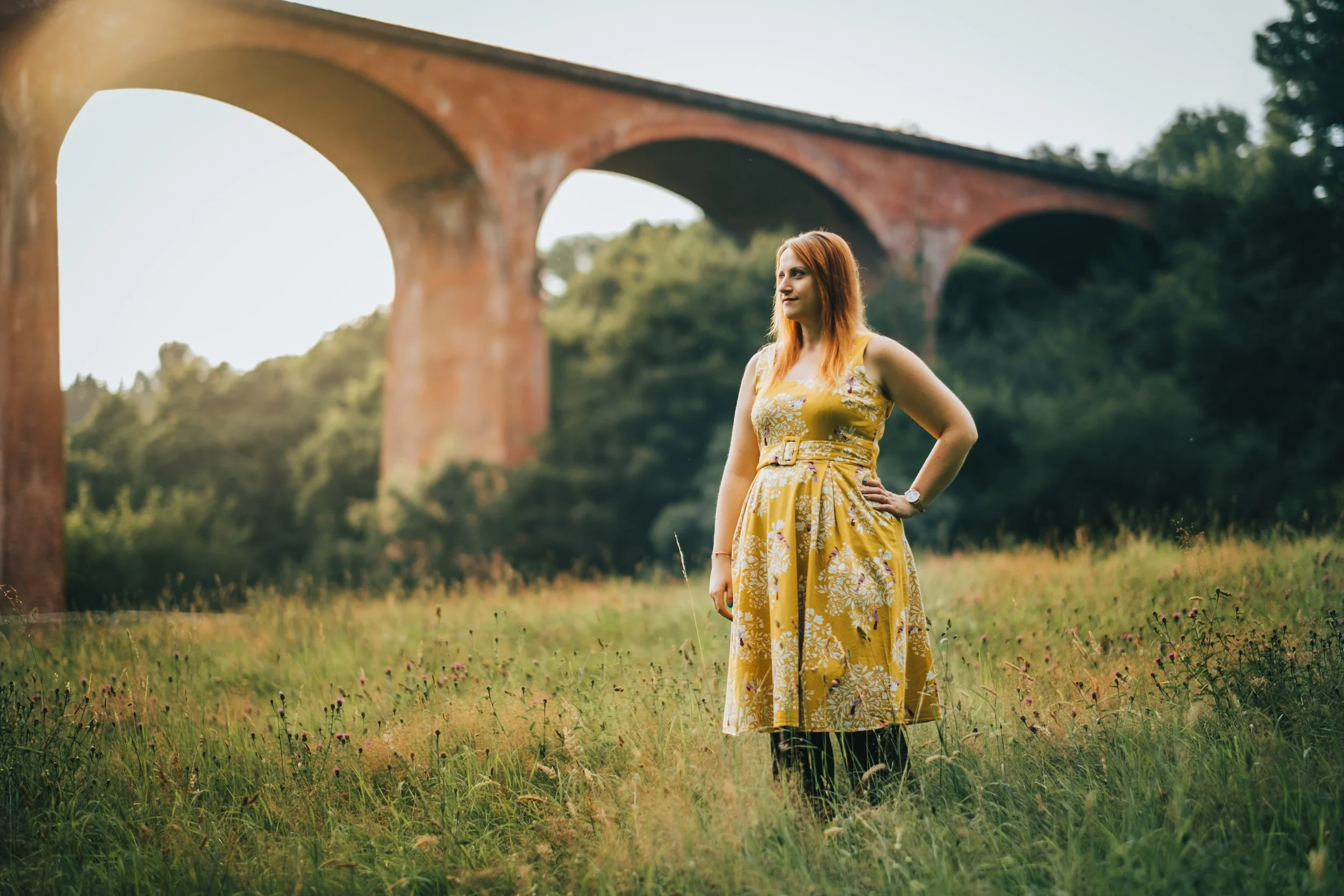 women stands in grass with saltburn viaduct behind her one summers evening
