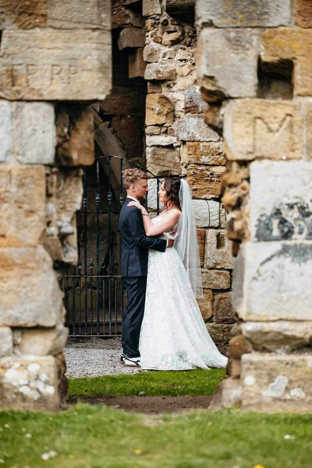 Bride and groom framed by a doorway in the historic ruins at Danby Castle