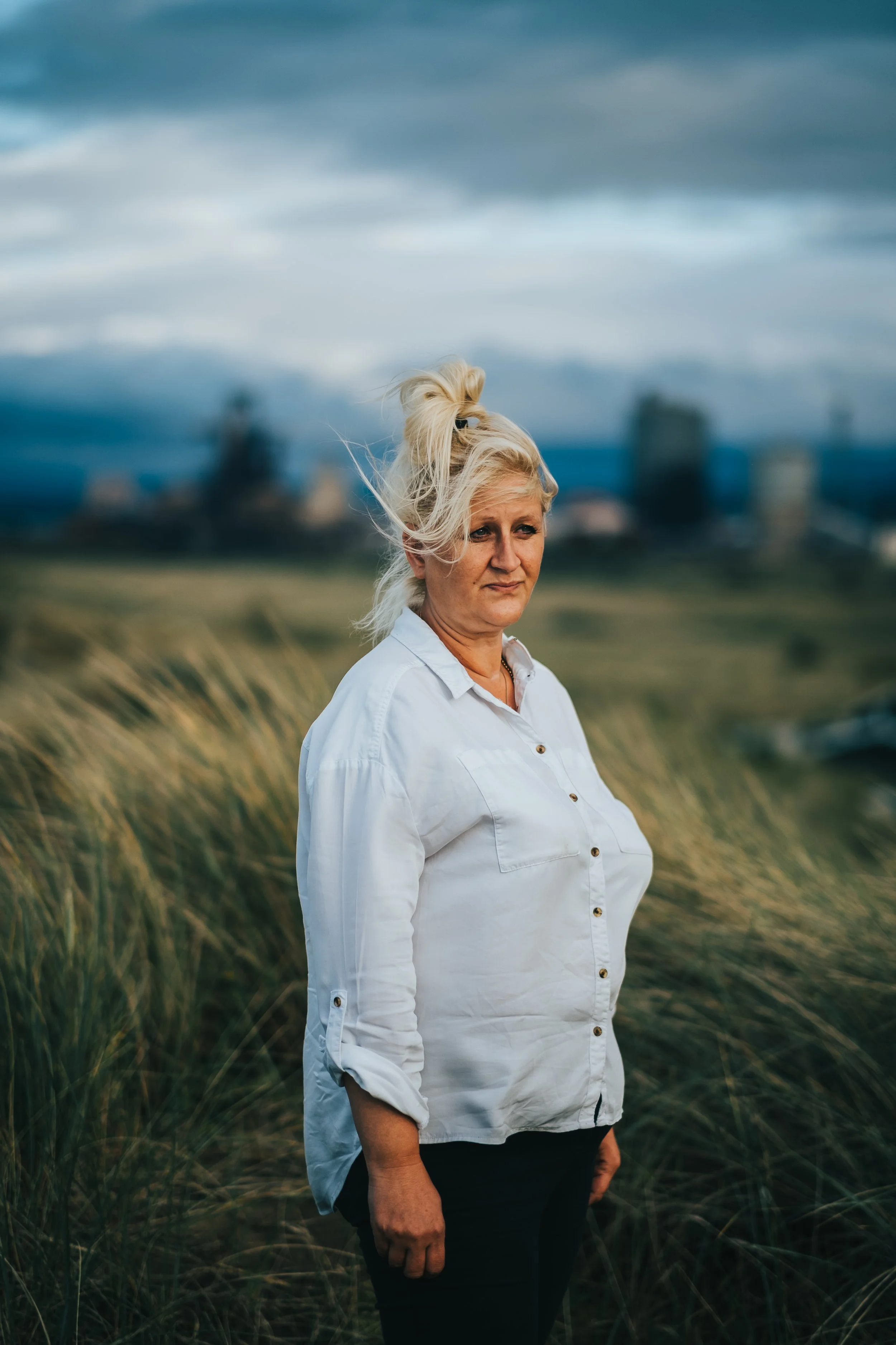 Middlesgaed women stand ontop of dunes in golden hour and looks into the distance