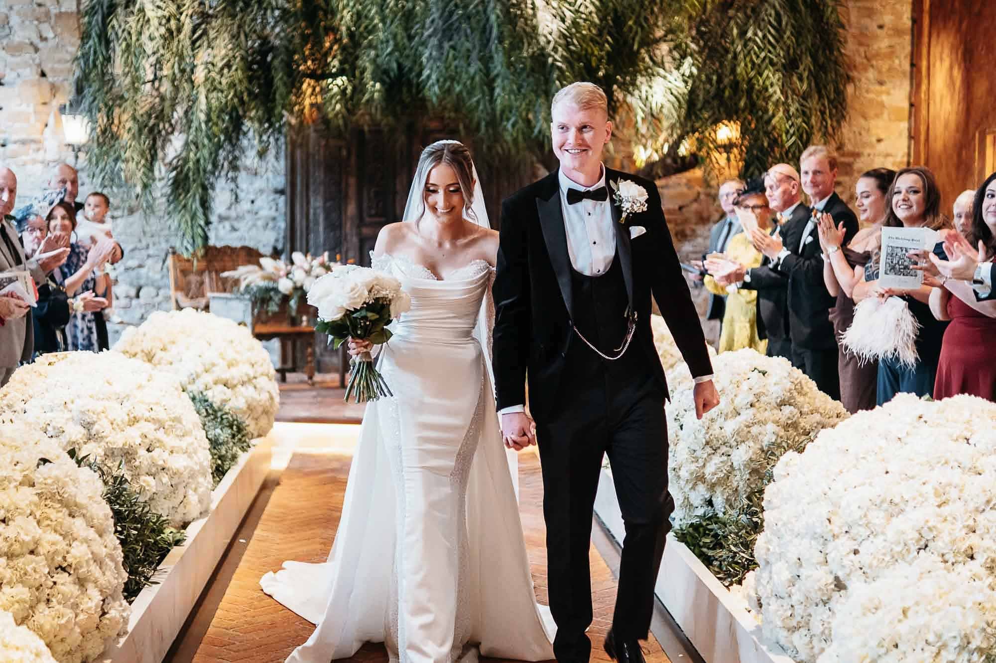 Bride and groom walking back down the runway aisle beneath the willow at The Croft Hotel