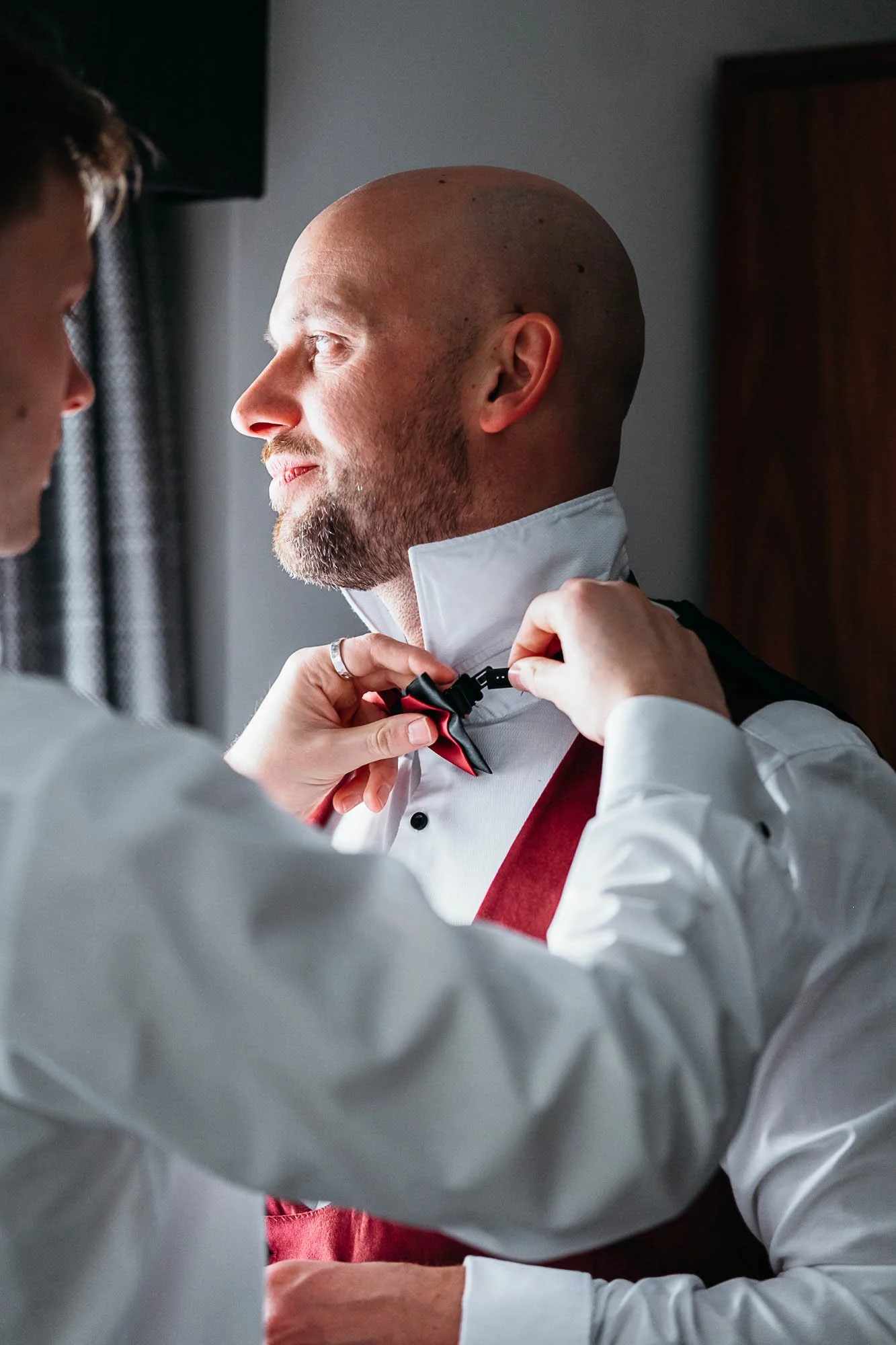 Groom having his red bow tie fastened before his wedding at The Croft Hotel