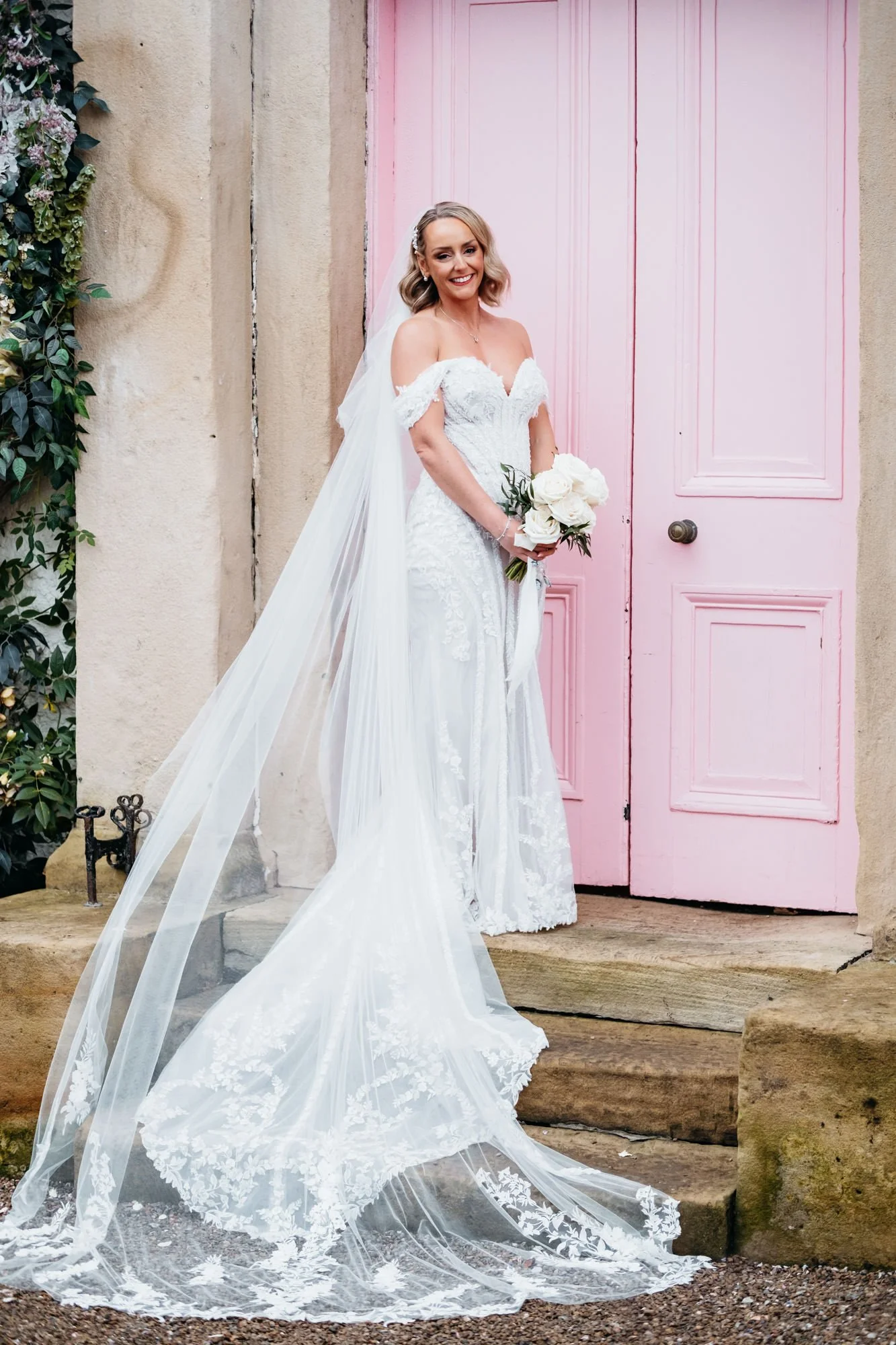 Bride with a long train on the steps of the pink door, The Croft Hotel, Croft-on-Tees