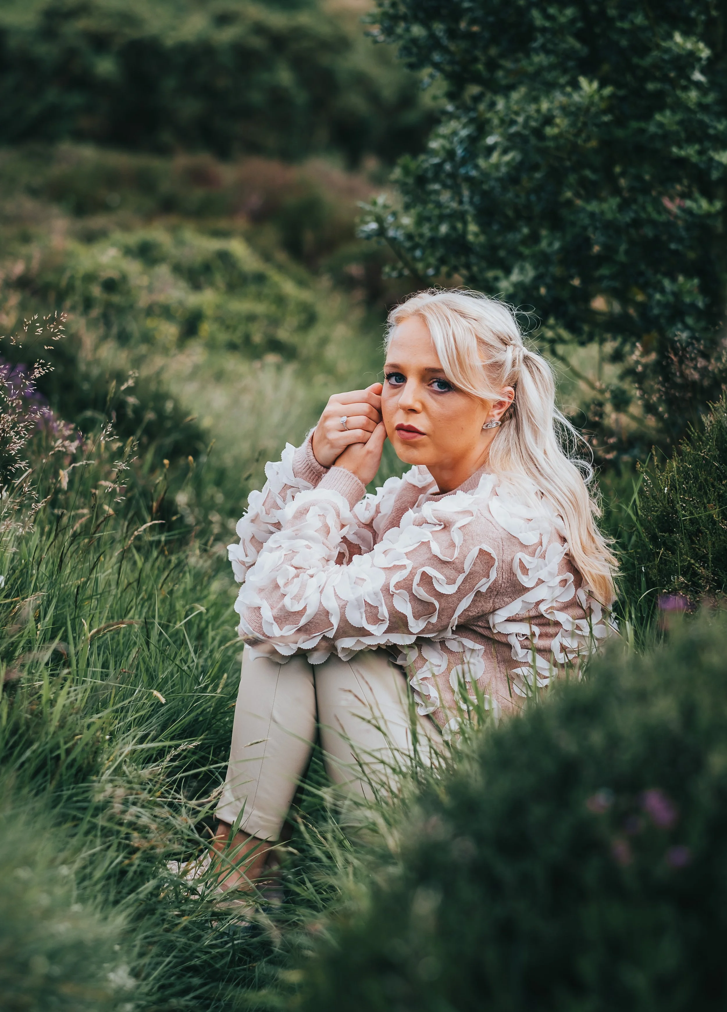 Women sits in grass and poses for the camera