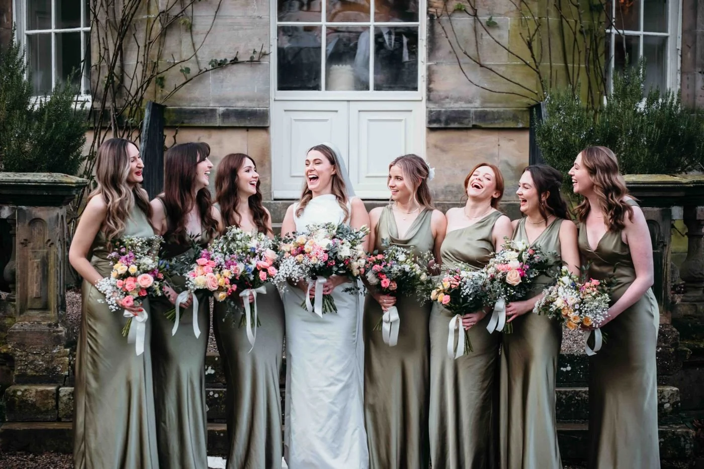 Bride and bridesmaids in sage green lined up outside the Main House, Middleton Lodge